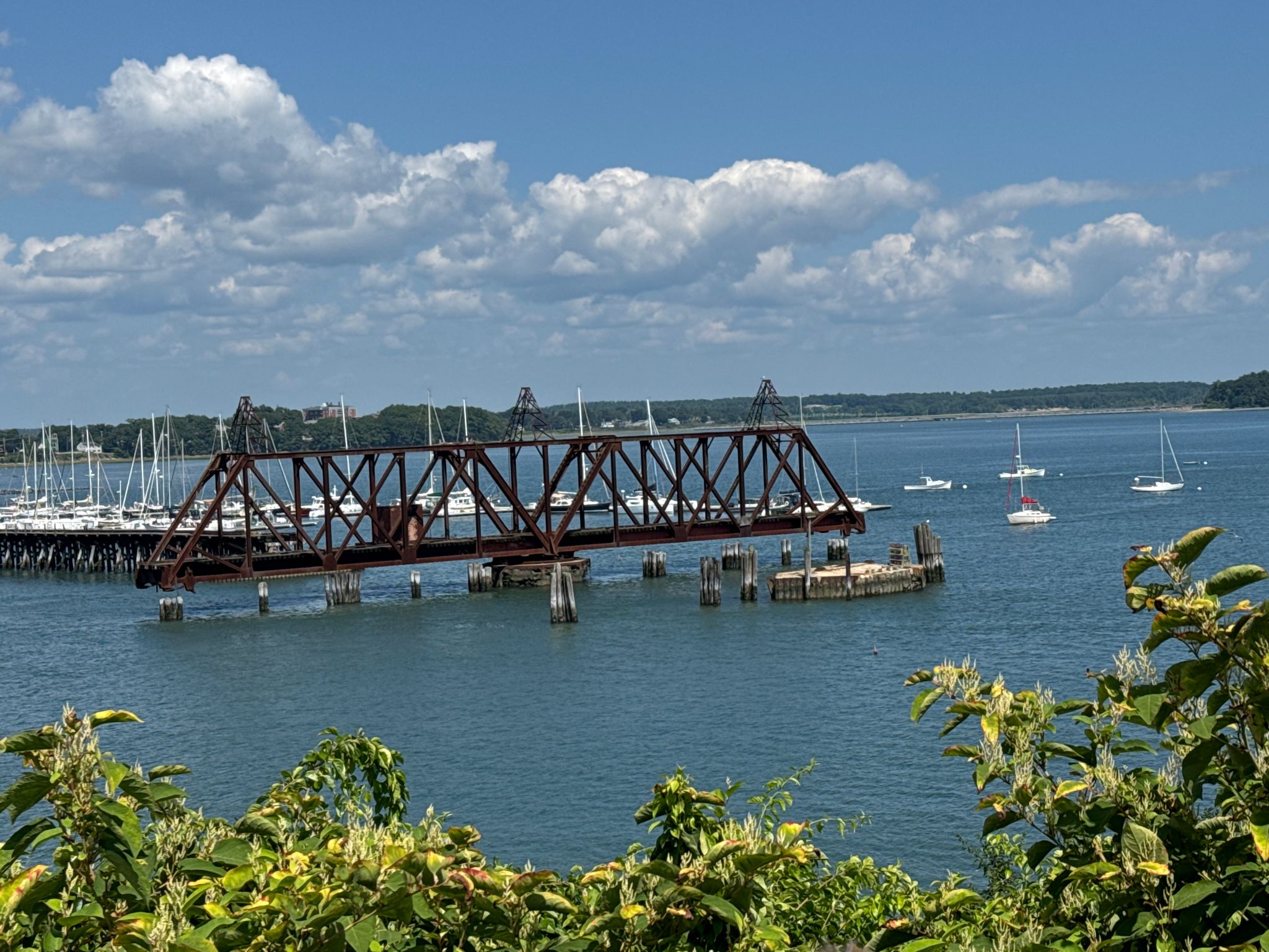 Sunny view of a metal bridge over water with many boats. - Baxter Boulevard Bike Route – Views of Casco Bay loop from Portland