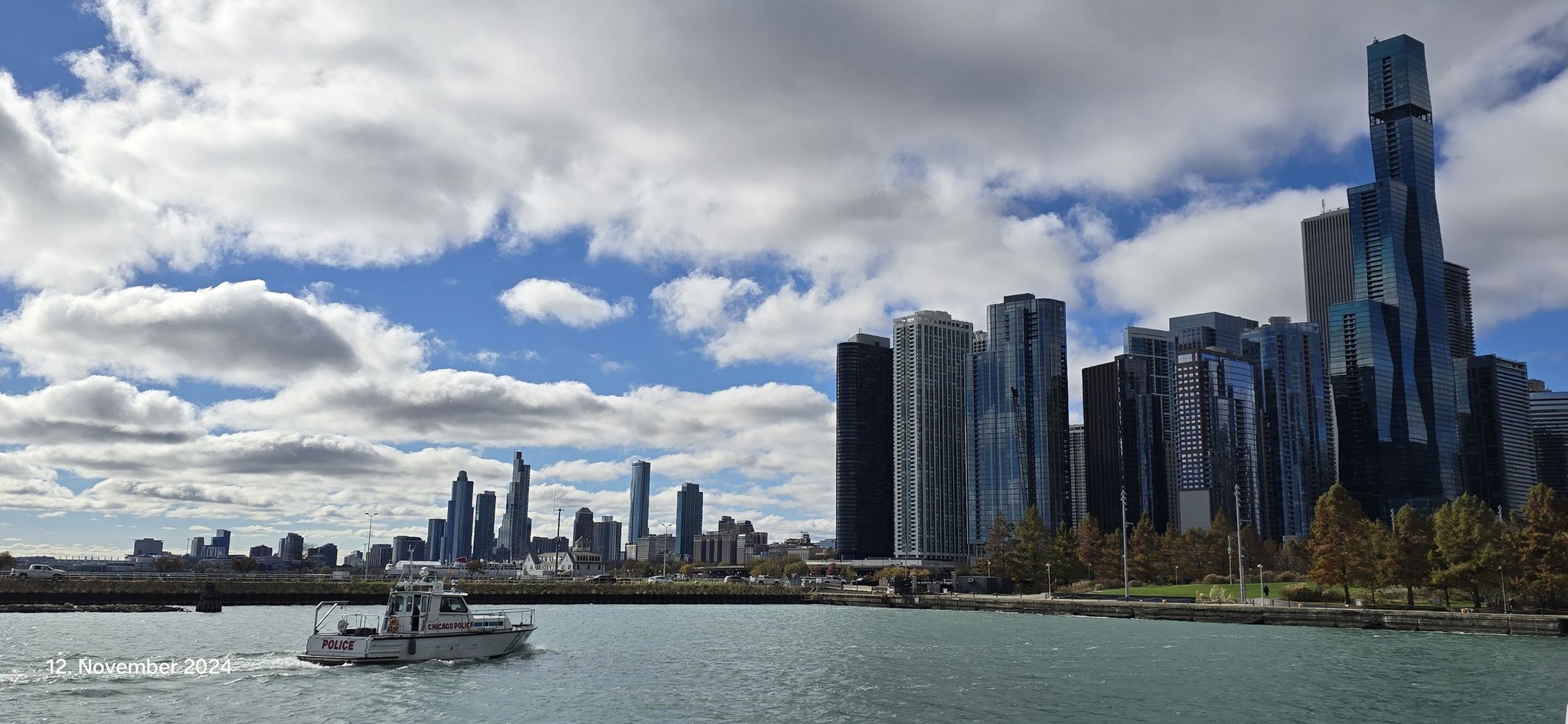 A boat on water with a city skyline under a cloudy sky. - Northwestern Medicine Wellness Way Fitness Trail