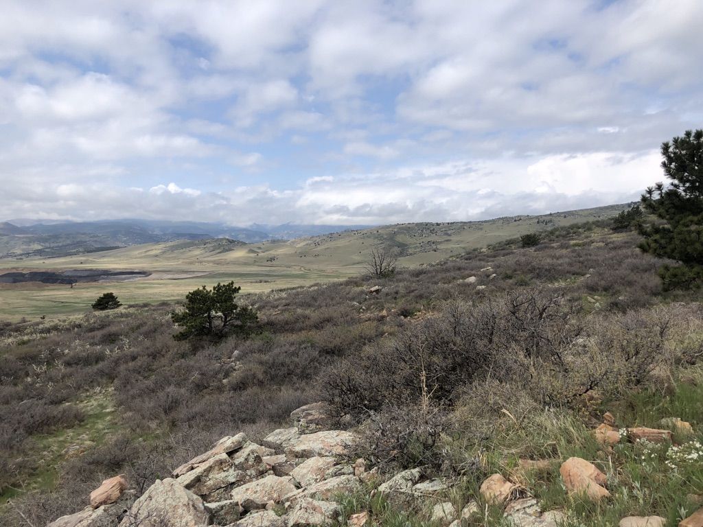 Overcast view of a vast, rocky, brush-covered landscape with distant mountains. - Eagle Wind Trail Loop