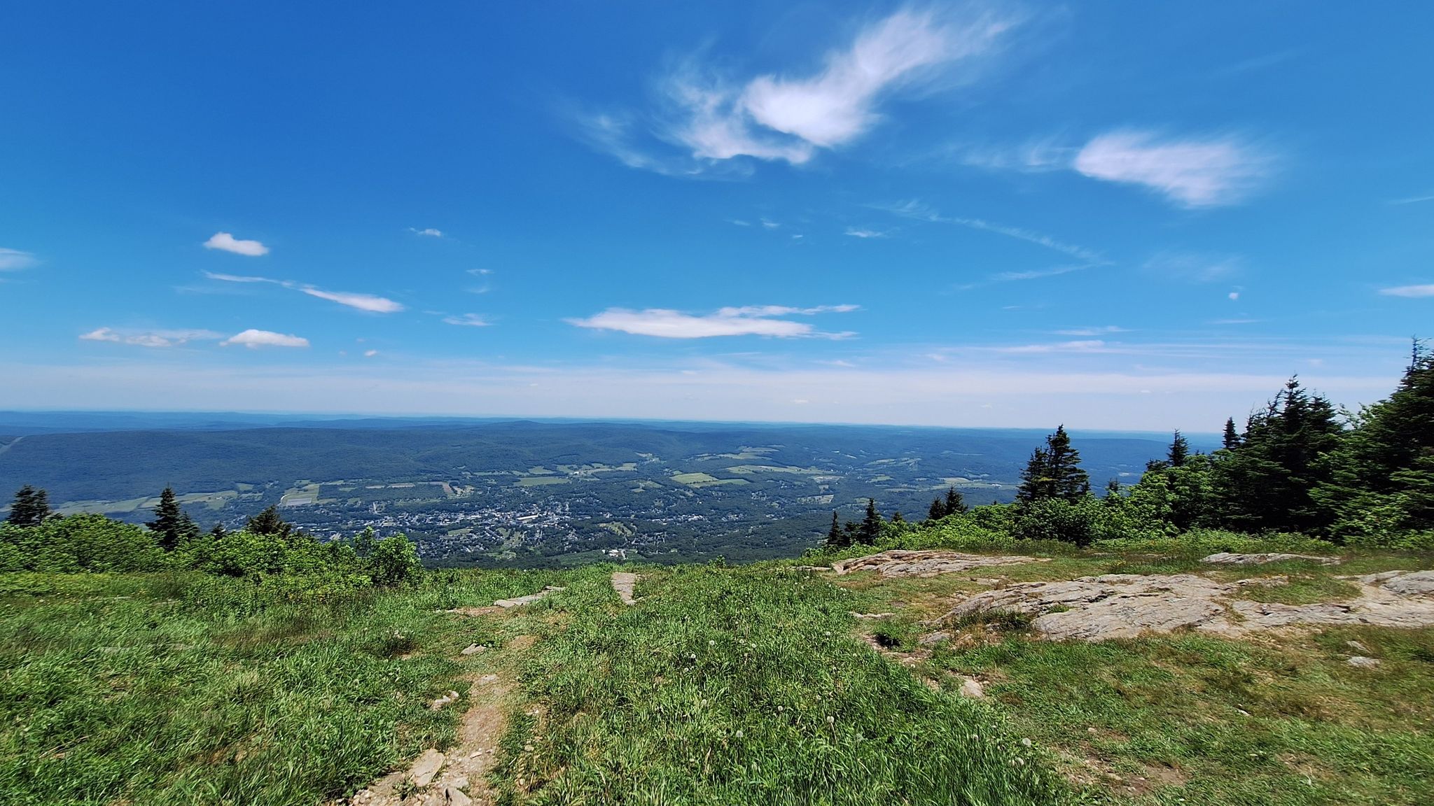 Panoramic mountain view with a distant town under a bright blue sky. - Thoreau’s Footsteps loop from Notch Road