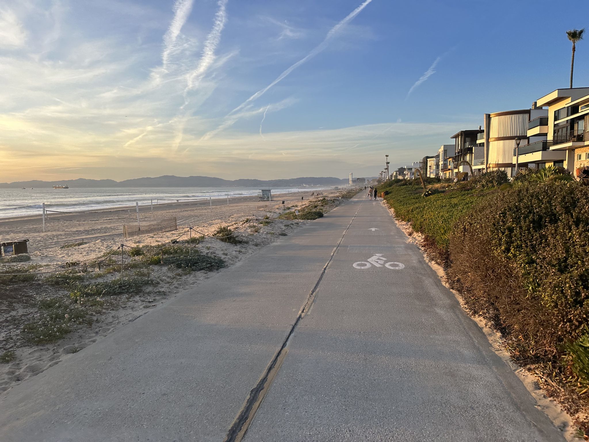 A paved beach path with houses, sand, and ocean under a colorful sky. - Manhattan Beach and Pier – Manhattan Beach loop from Redondo Beach