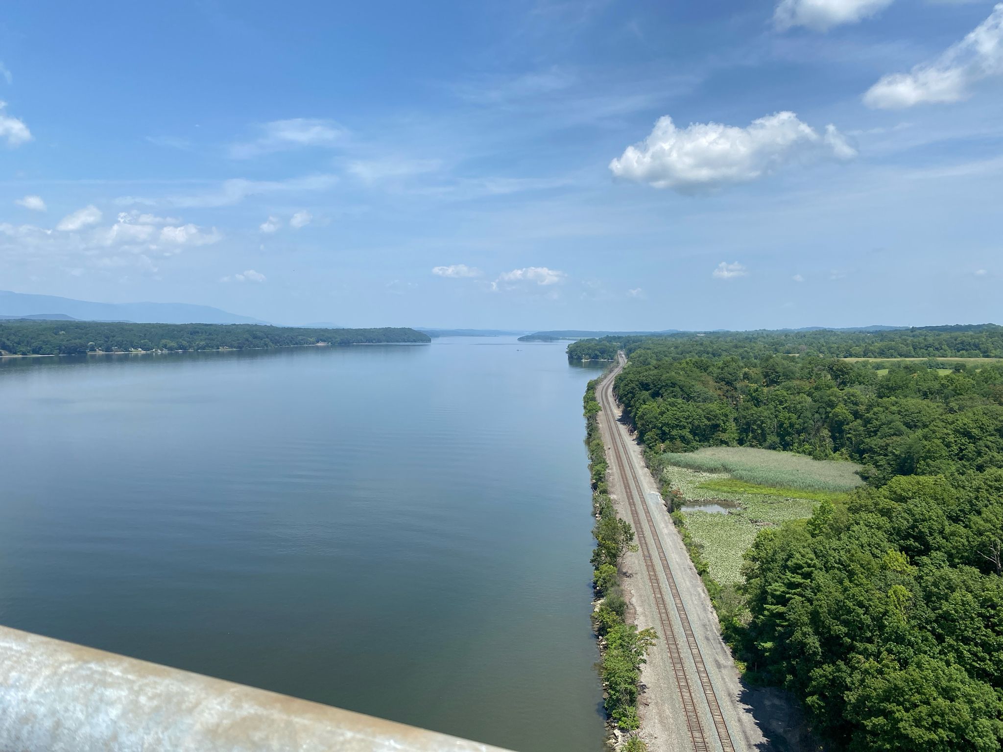 Expansive body of water next to train tracks, surrounded by green landscape. - Claverack Creek Waterfall – River Road - Fantastic Ride loop from Hudson
