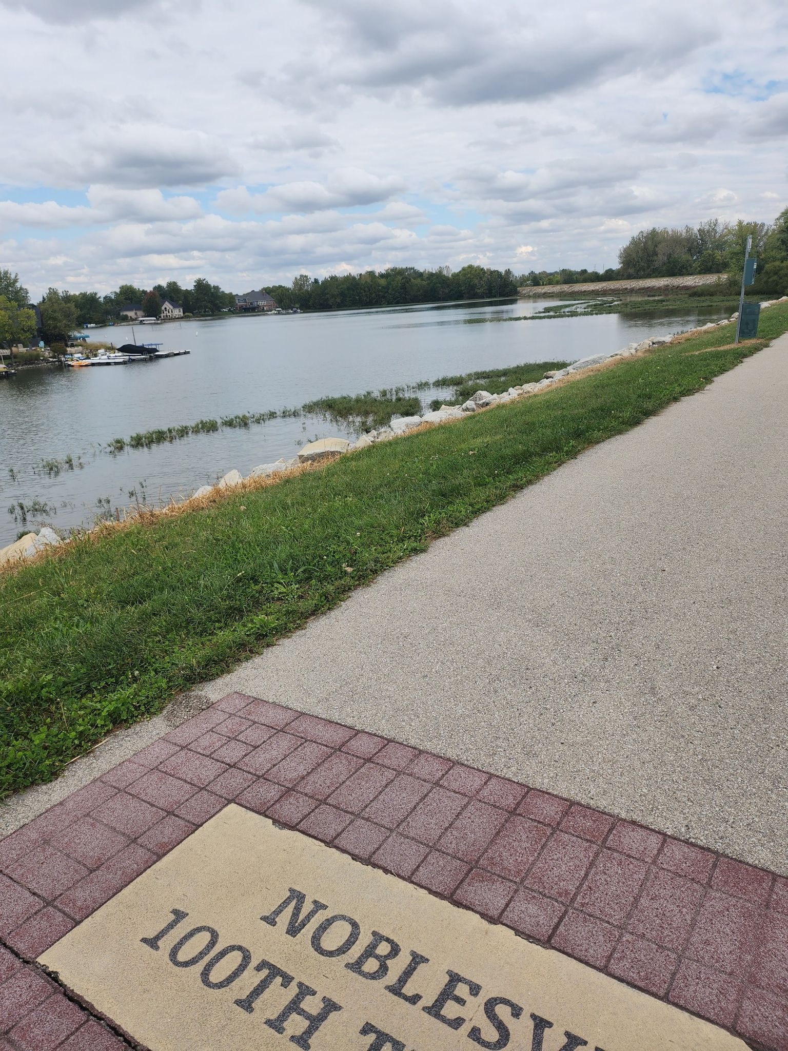 Paved path next to a lake with boats and marshy reeds. - Bike loop from Hamilton County
