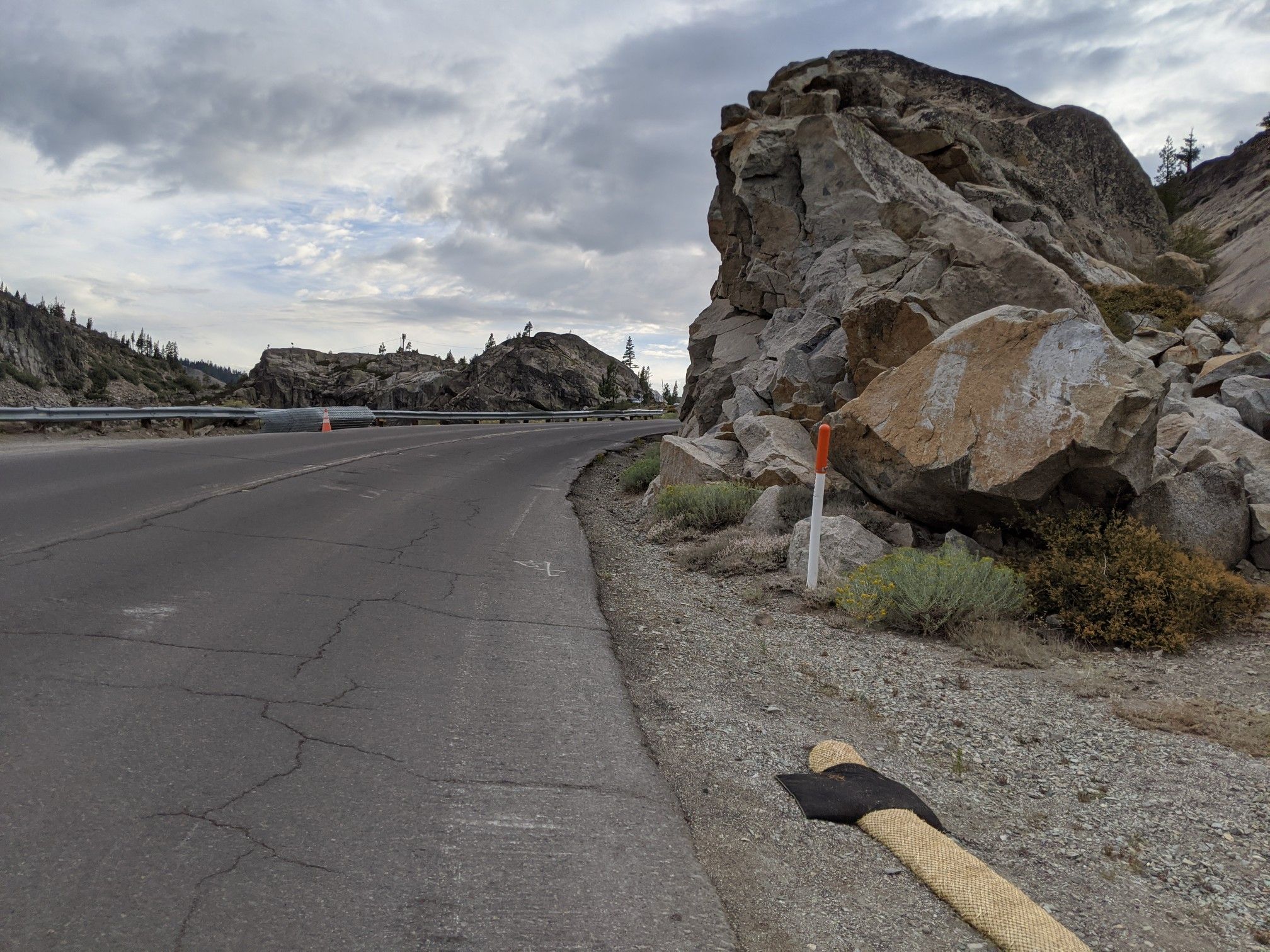 A curved road next to large rocks under an overcast sky. - Donner Ski Ranch – View of Donner Lake loop from Cisco Grove