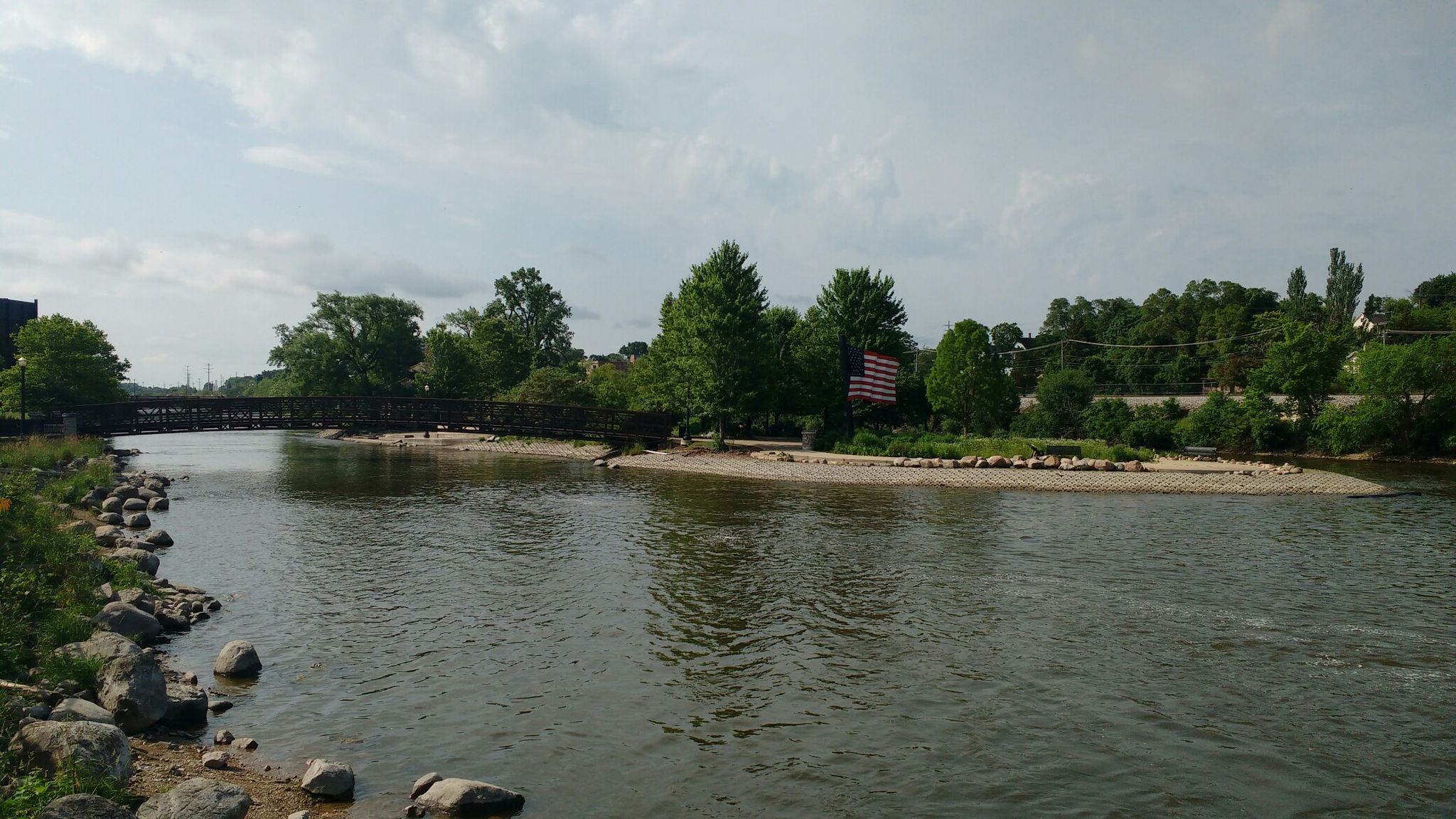 A wide river flows past a bridge and a small treed island. - Norton Woods – Fox River Trail loop from St. Charles