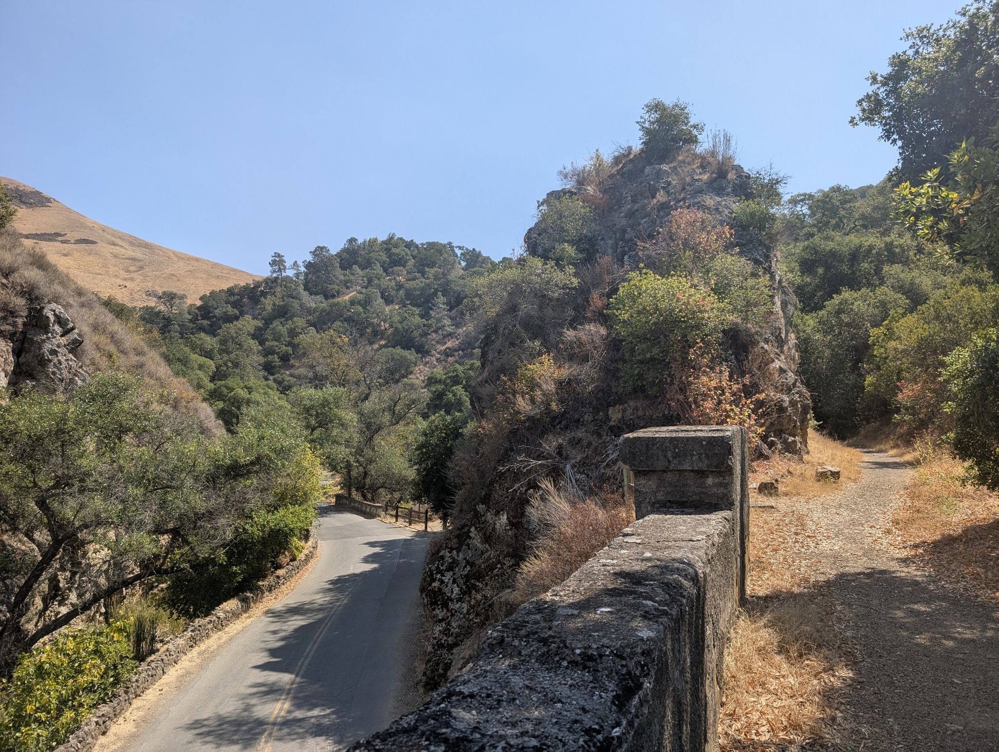 Stone wall overlooking a winding road and a dirt trail through rocky hills. - Upper Penitencia Creek – Inspiration Point loop from Great Mall/Main