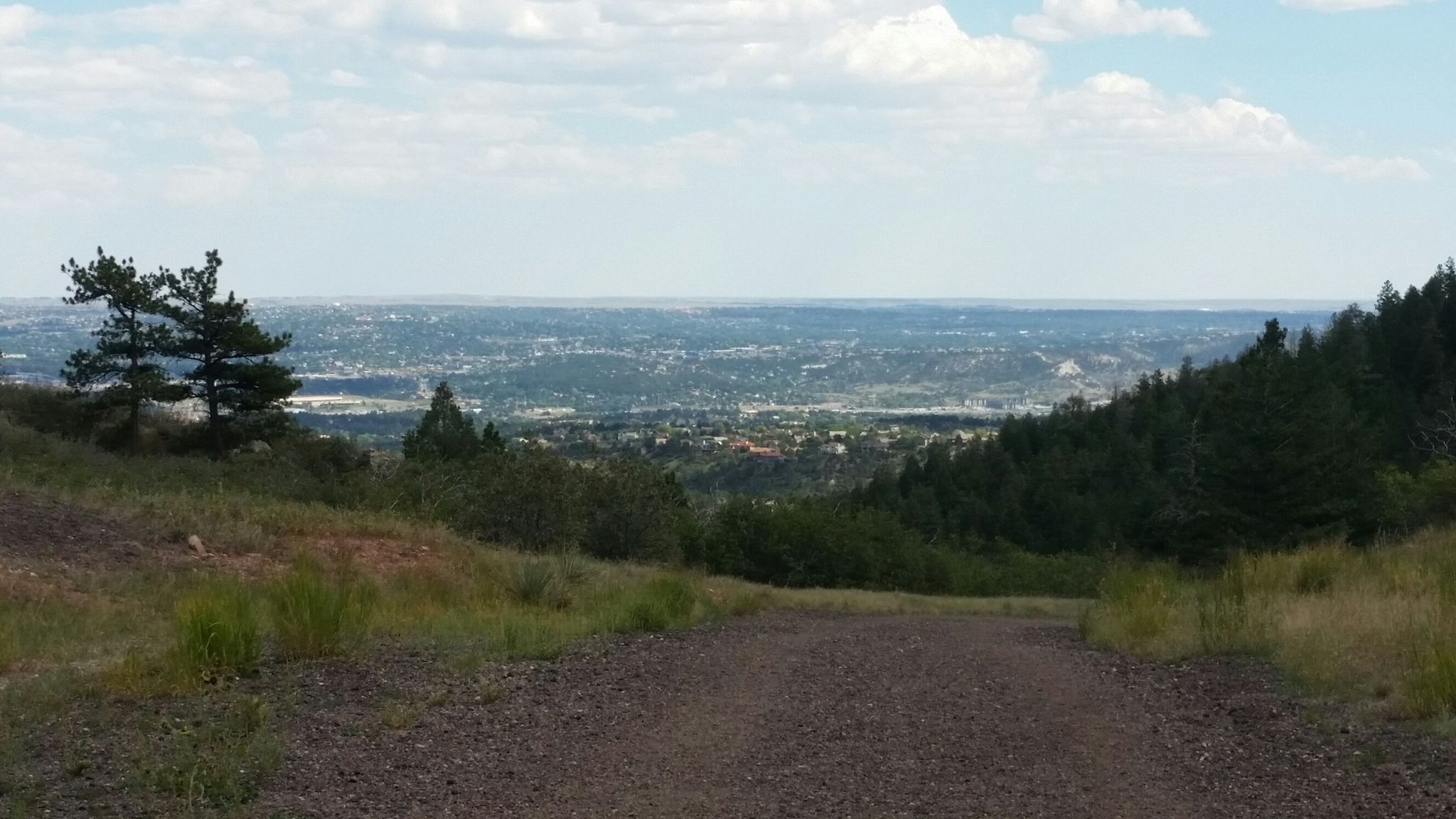 Dirt path overlooking a distant city under a cloudy sky. - Blodgett Peak Open Space Connector Loop