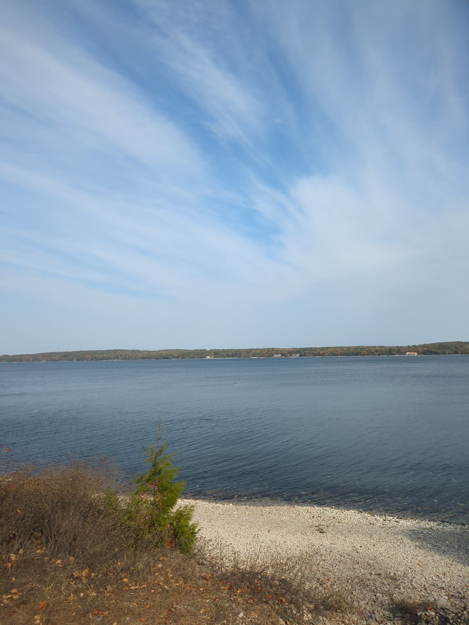 Calm blue lake with a distant forested shoreline under a bright sky. - Potawatomi State Park loop from Potawatomi State Park