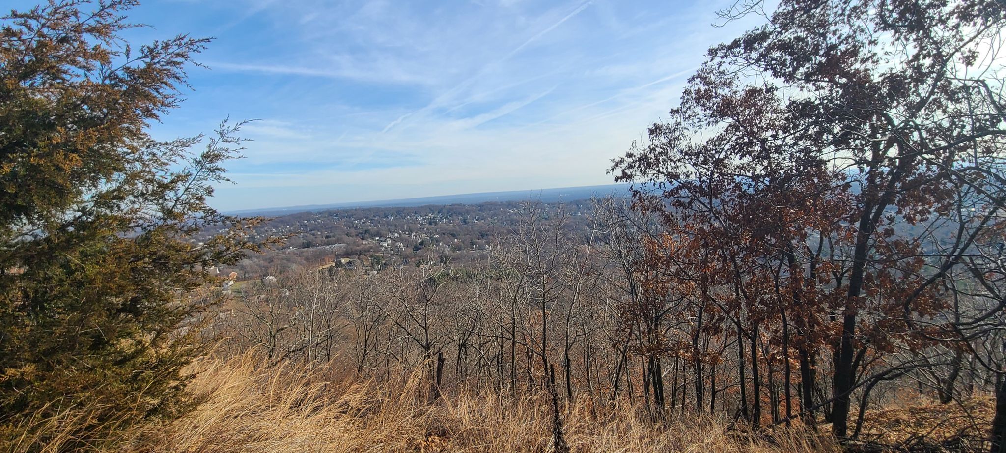 Panoramic view of a distant town from a hill on a sunny day. - Summit Trail Loop