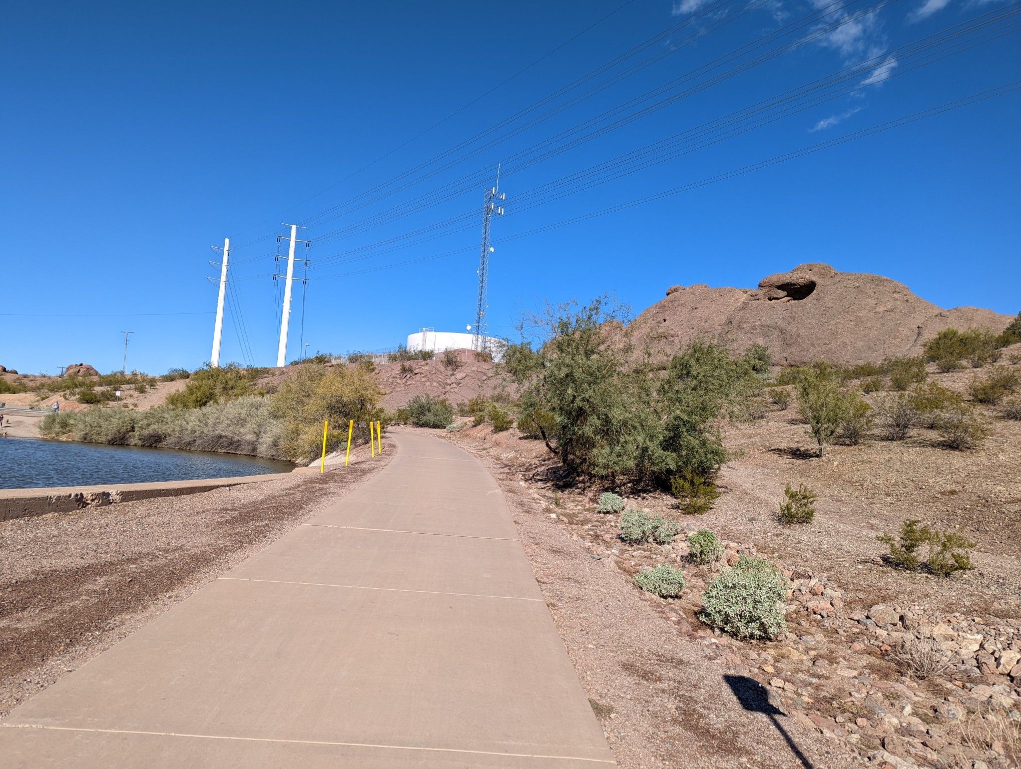 Paved path next to water, desert landscape, rocky hills, clear blue sky. - Tempe Town Lake – Arizona Falls loop from Dorsey/Apache Blvd
