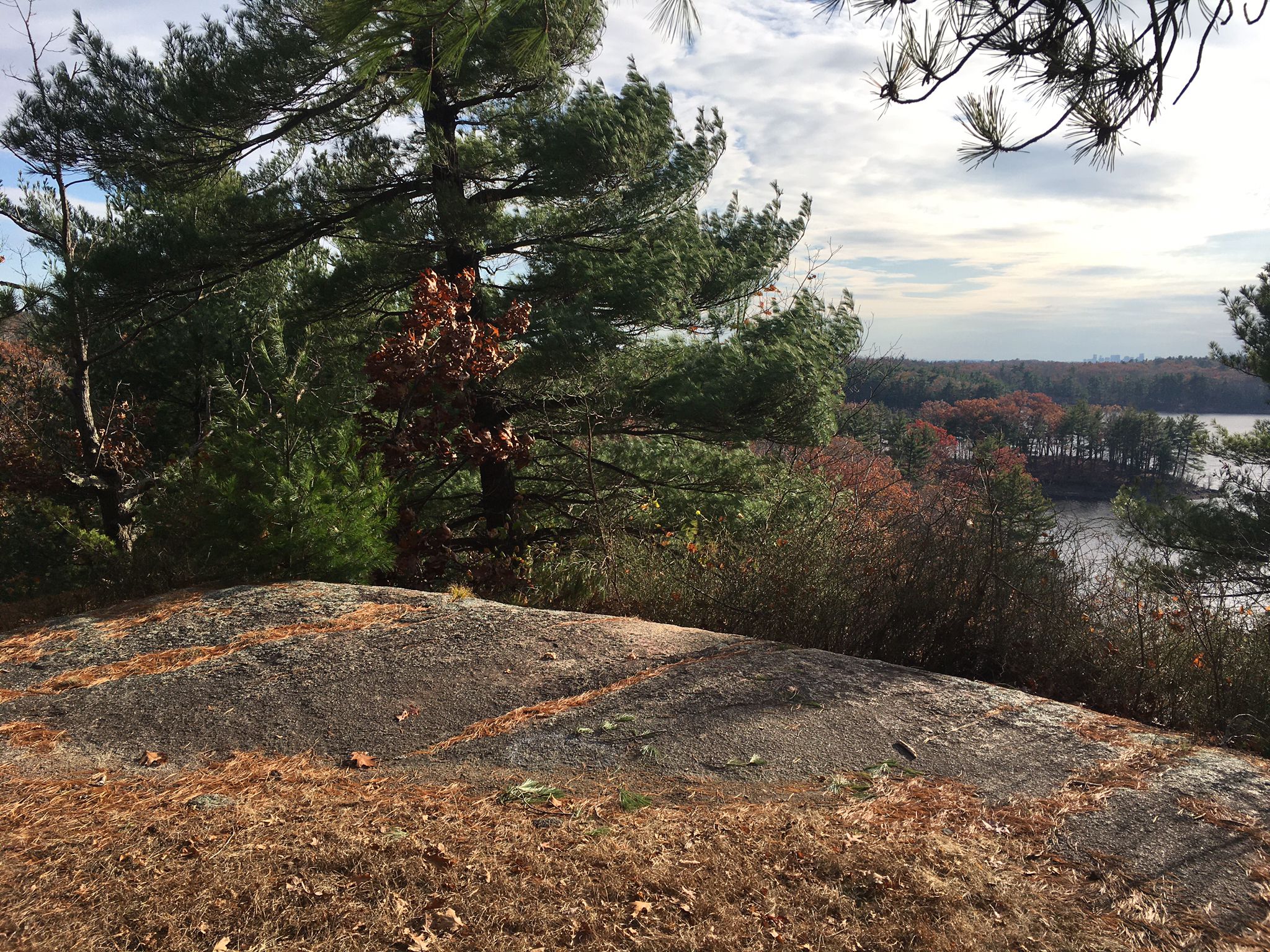 Rocky outcrop overlooking a lake and forest with autumn colors. - Balanced Boulder – Scenic Overlook loop from Bow Ridge Conservation Area