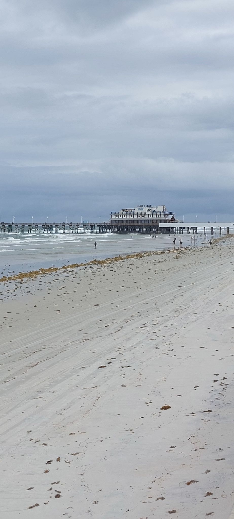 Overcast beach scene with a long pier extending into the ocean. - Daytona Beach Boardwalk