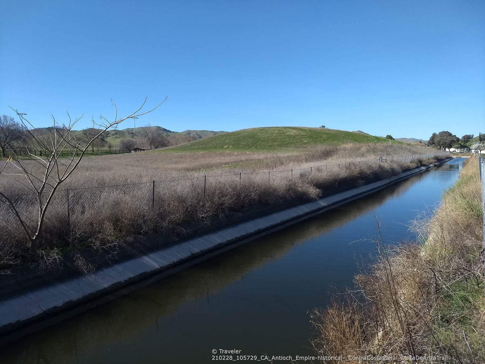 A canal flows beside dry grass and green hills under a clear sky. - Delta de Anza and Mokelumne Trail Loop