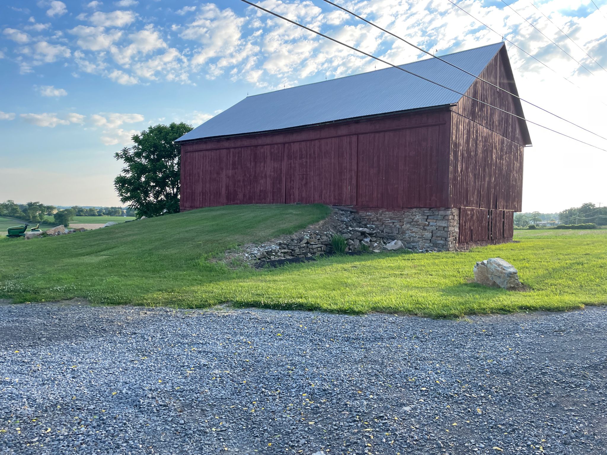Red barn on a grassy hill under a bright sky at golden hour. - Pine Grove Mills loop from Pine Grove Mills