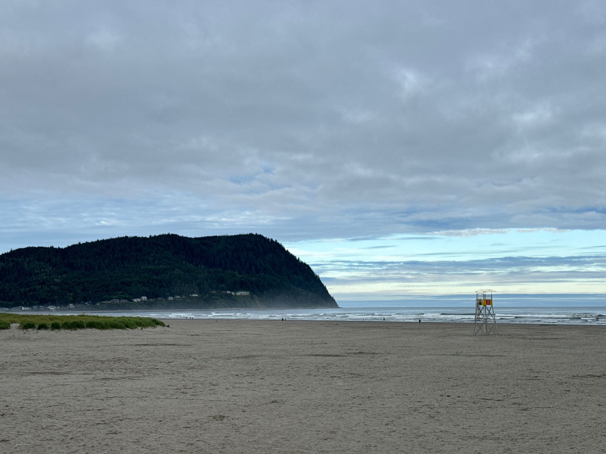 Wide sandy beach with a lifeguard stand, ocean, and a large forested headland. - Seaside Cove and Seltzer Park loop from Seaside
