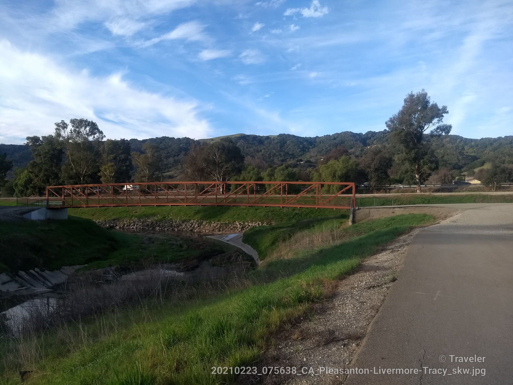 Orange pedestrian bridge over a dry creek, green hills under a bright sky. - Arroyo Mocho Trail – Arroyo Mocho Trail loop from West Dublin/Pleasanton