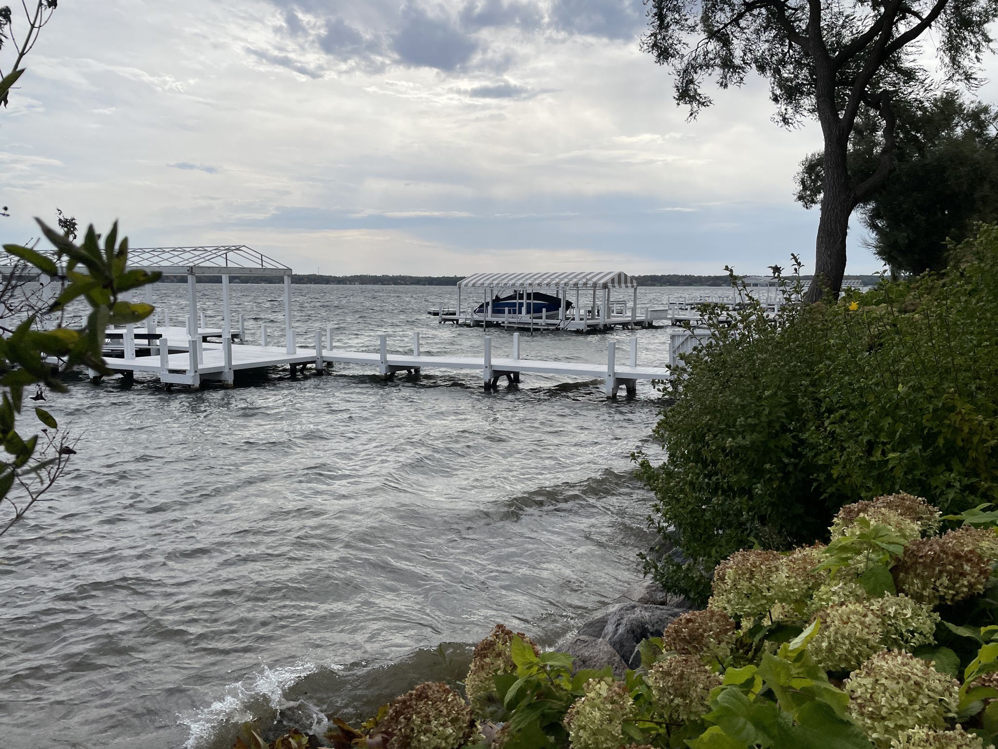 White wooden docks and covered boat slips on a choppy lake under cloudy skies. - Lake Geneva Shore Path