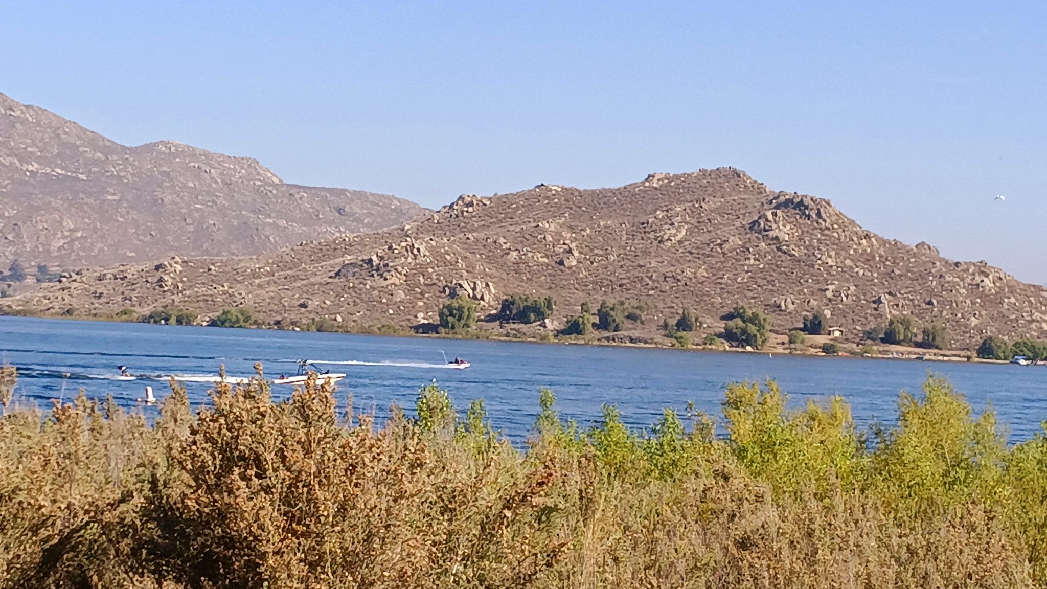 Boats on a blue lake with rocky mountains under a clear sky. - Lake Perris – Scenic Cycling Spot loop from Lake Perris