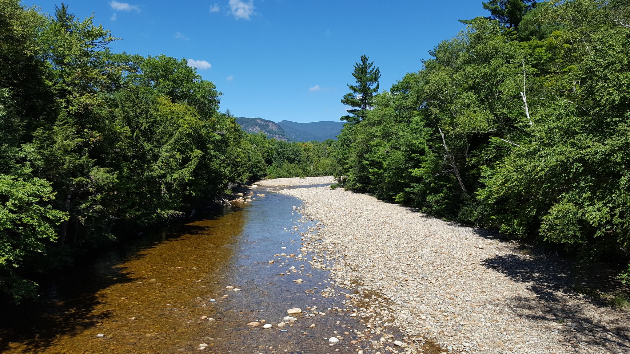 A clear river flows beside a wide gravel bank under a bright sky. - Mount Crawford, Stairs Mountain, and Mount Resolution