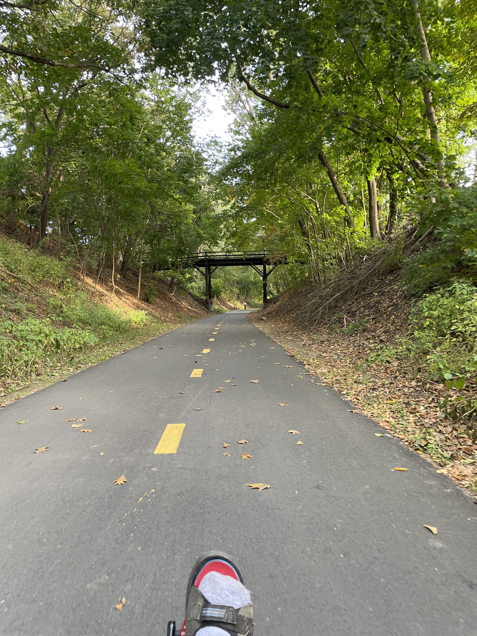 Paved path leading to a distant bridge, seen from a person's perspective. - Cochituate Rail Trail – Lake Cochituate (Middle Pond) loop from Jordan's Furniture