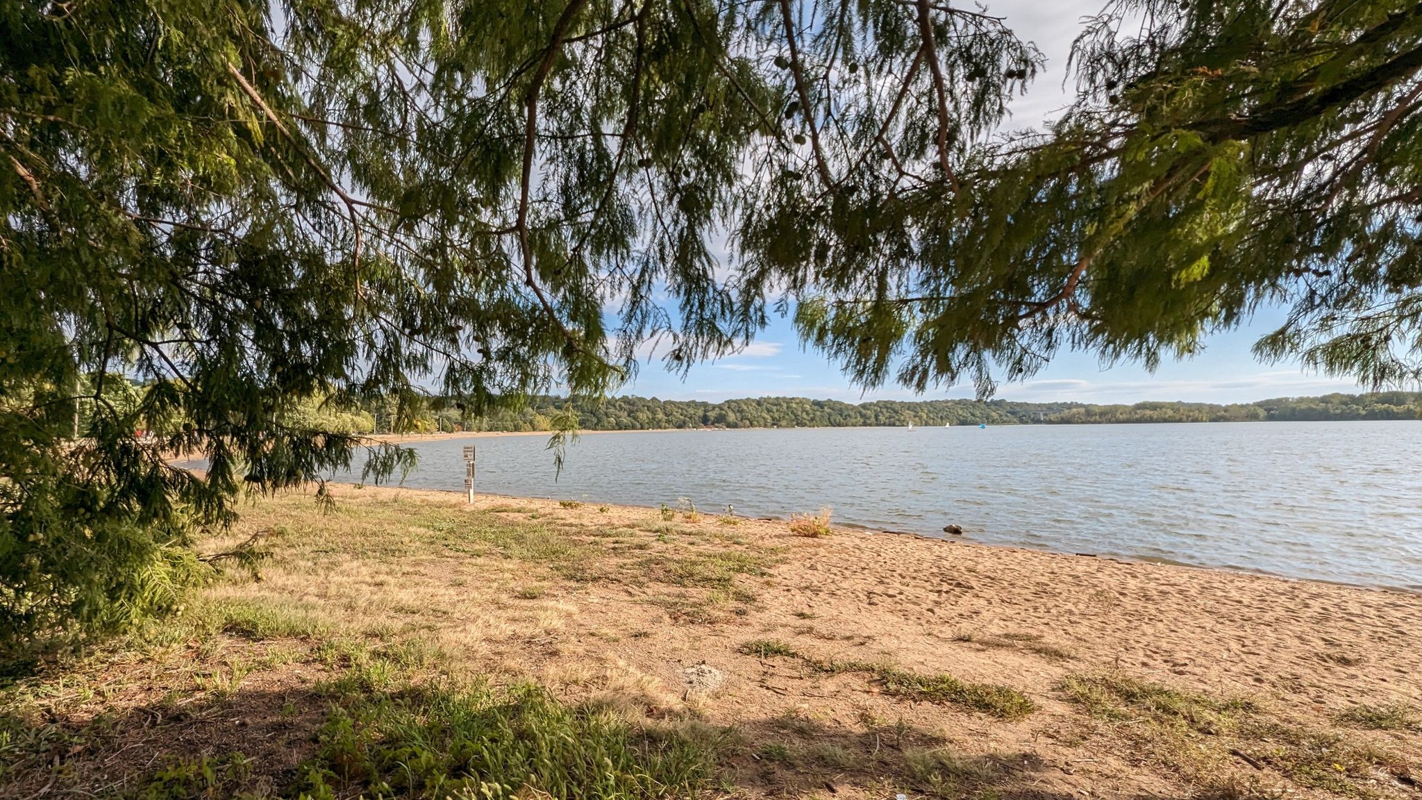 Sandy beach by a lake, framed by overhanging tree branches. - View of Creve Coeur Lake – View of the Missouri River loop from Olive at Fernview