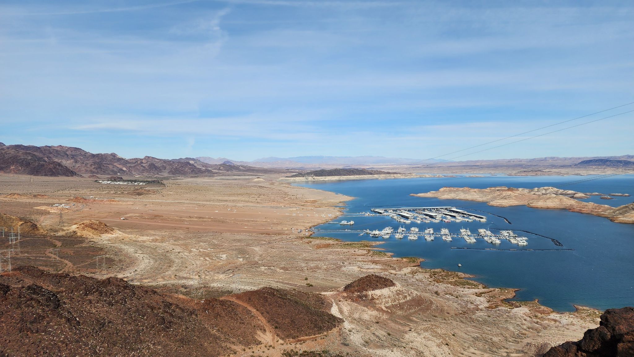 Marina on a large lake surrounded by dry hills under a partly cloudy sky. - River Mountains Loop Trail