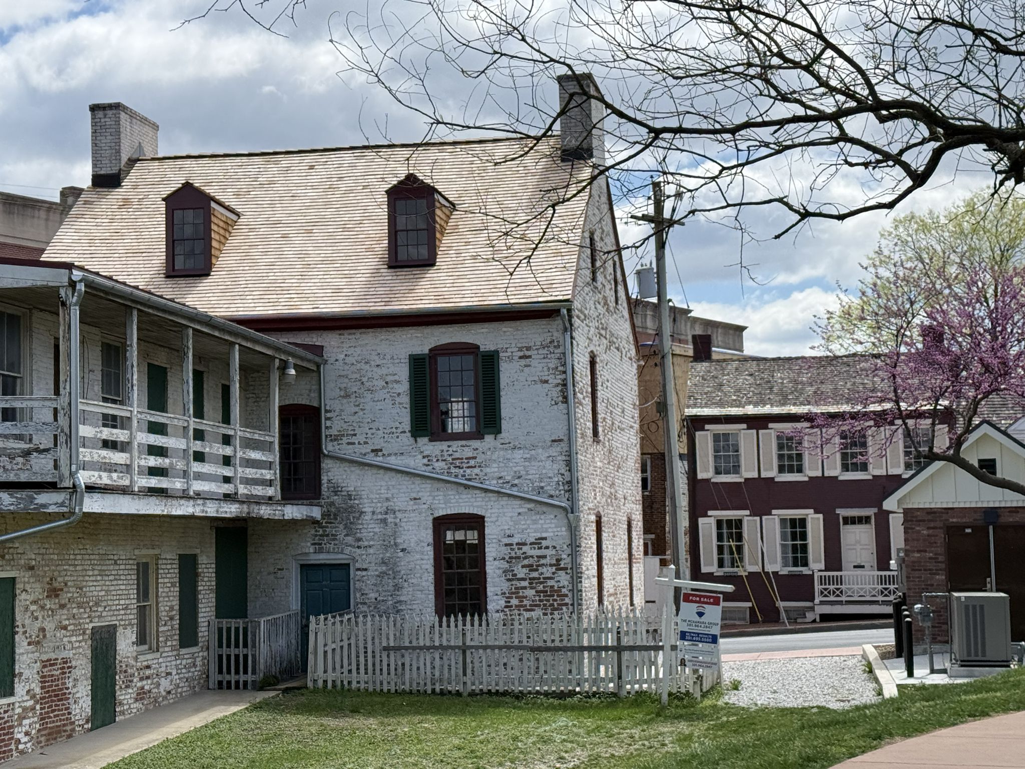Historic white and red brick buildings with dormer windows under a cloudy sky. - Carroll Creek Linear Park
