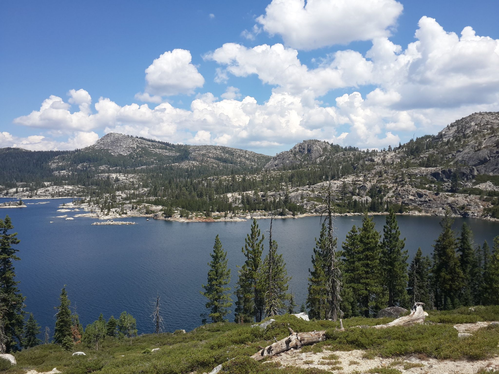 Scenic lake surrounded by forested mountains under a partly cloudy sky. - Loon Lake via Rubicon Trail