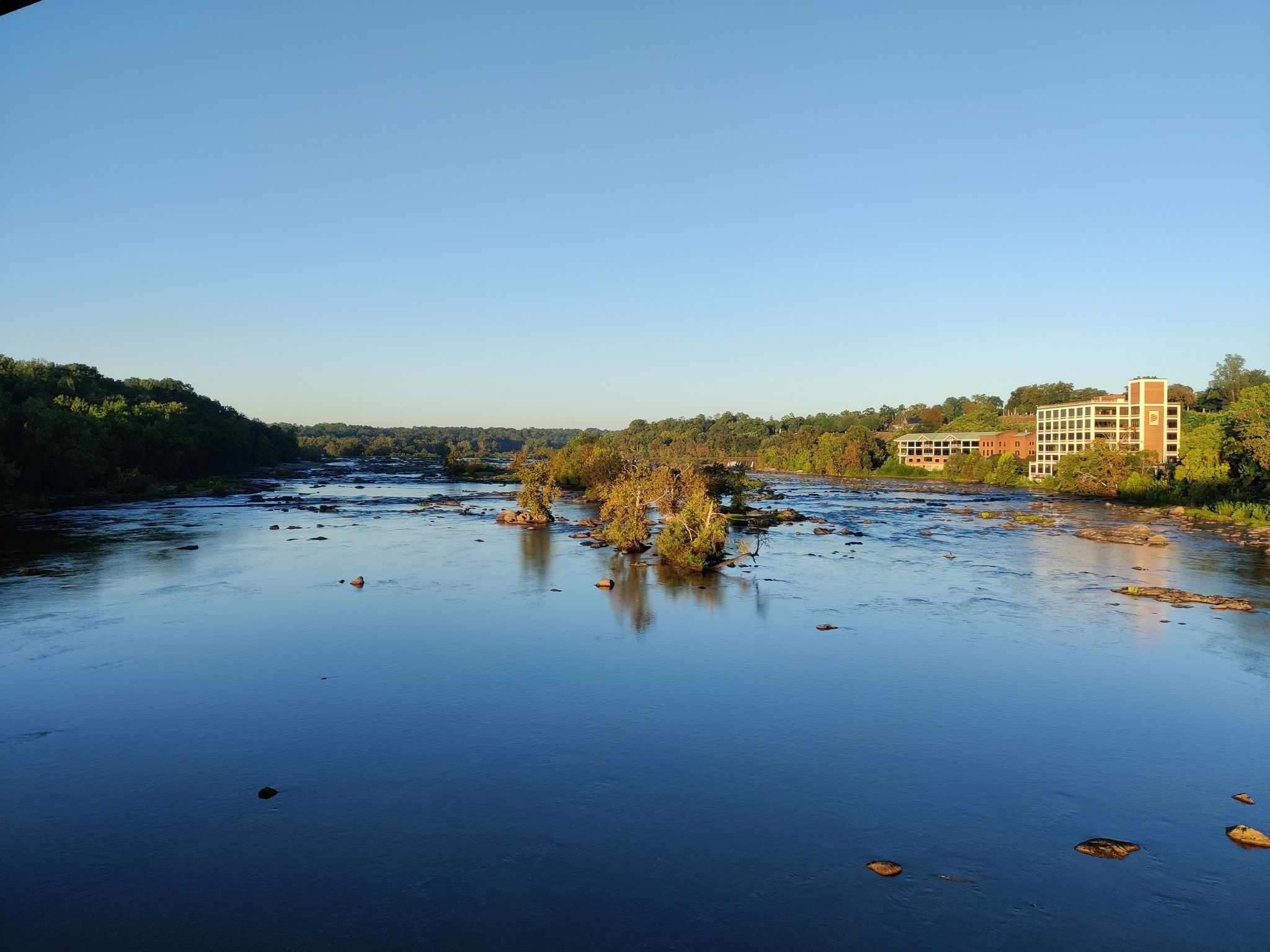 Wide river with small tree islands, flanked by forests and buildings. Golden hour. - Belle Isle and North Bank Trail Loop