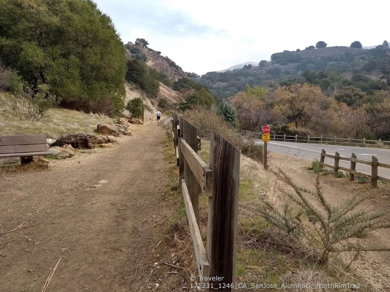 A dirt path with a wooden fence alongside a road, person walking uphill. - Upper Penitencia Creek – Alum Rock Park loop from Great Mall
