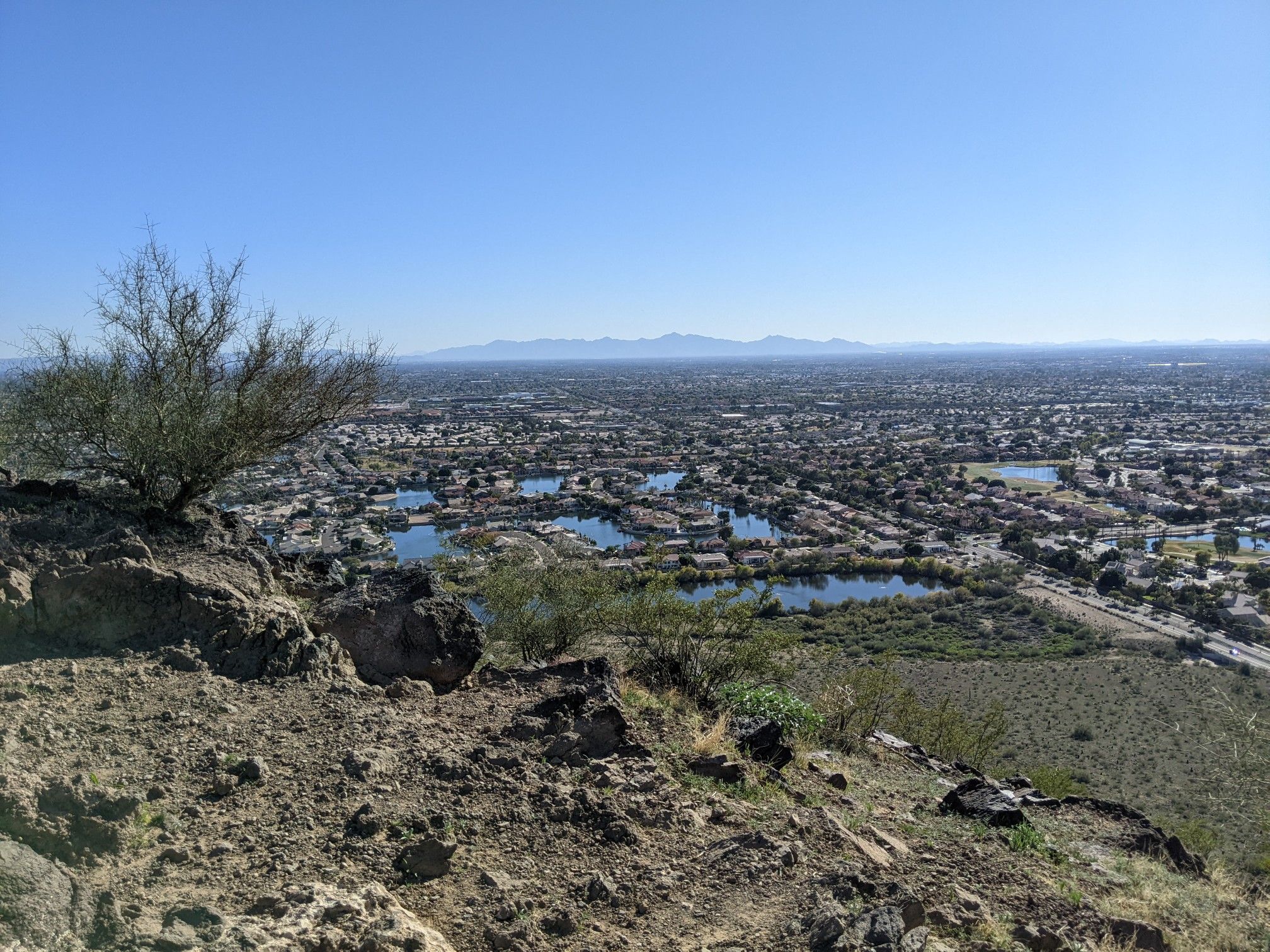 Elevated view of a city with lakes and distant mountains under clear sky. - H-2 Trail and H-1 Trail Loop