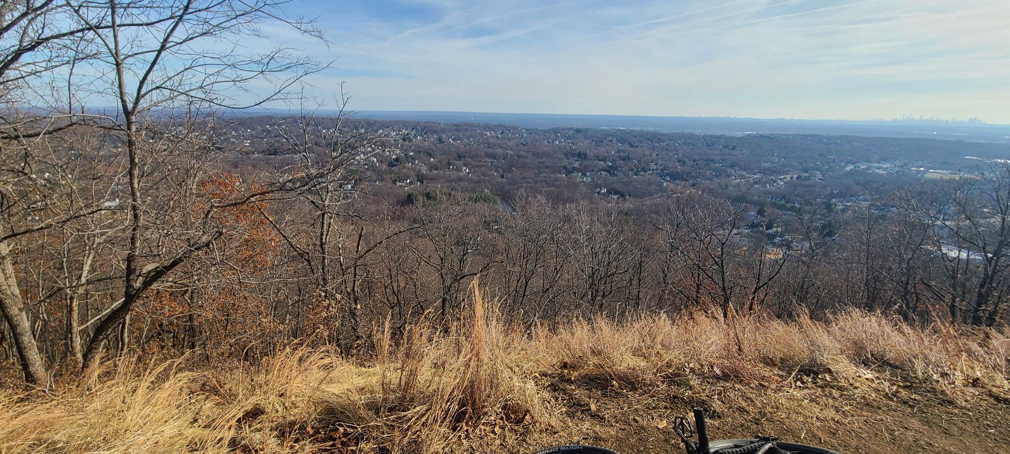 Wide view of a distant landscape from a hill, bike visible. - Summit Trail Loop