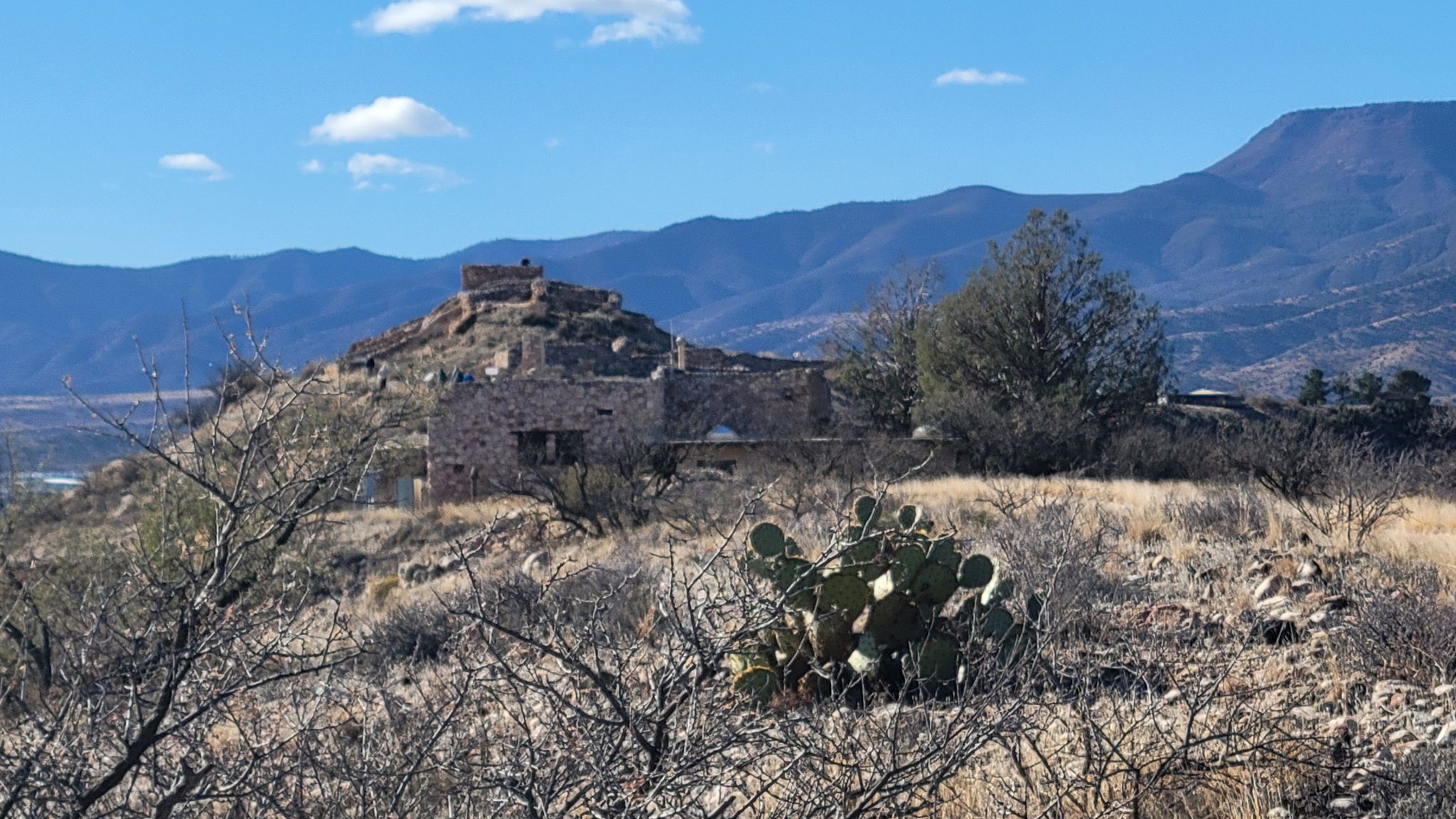 Ancient stone ruins on a hill with cactus, distant mountains. - Tuzigoot Pueblo and Tavasci Marsh Overlook Trail