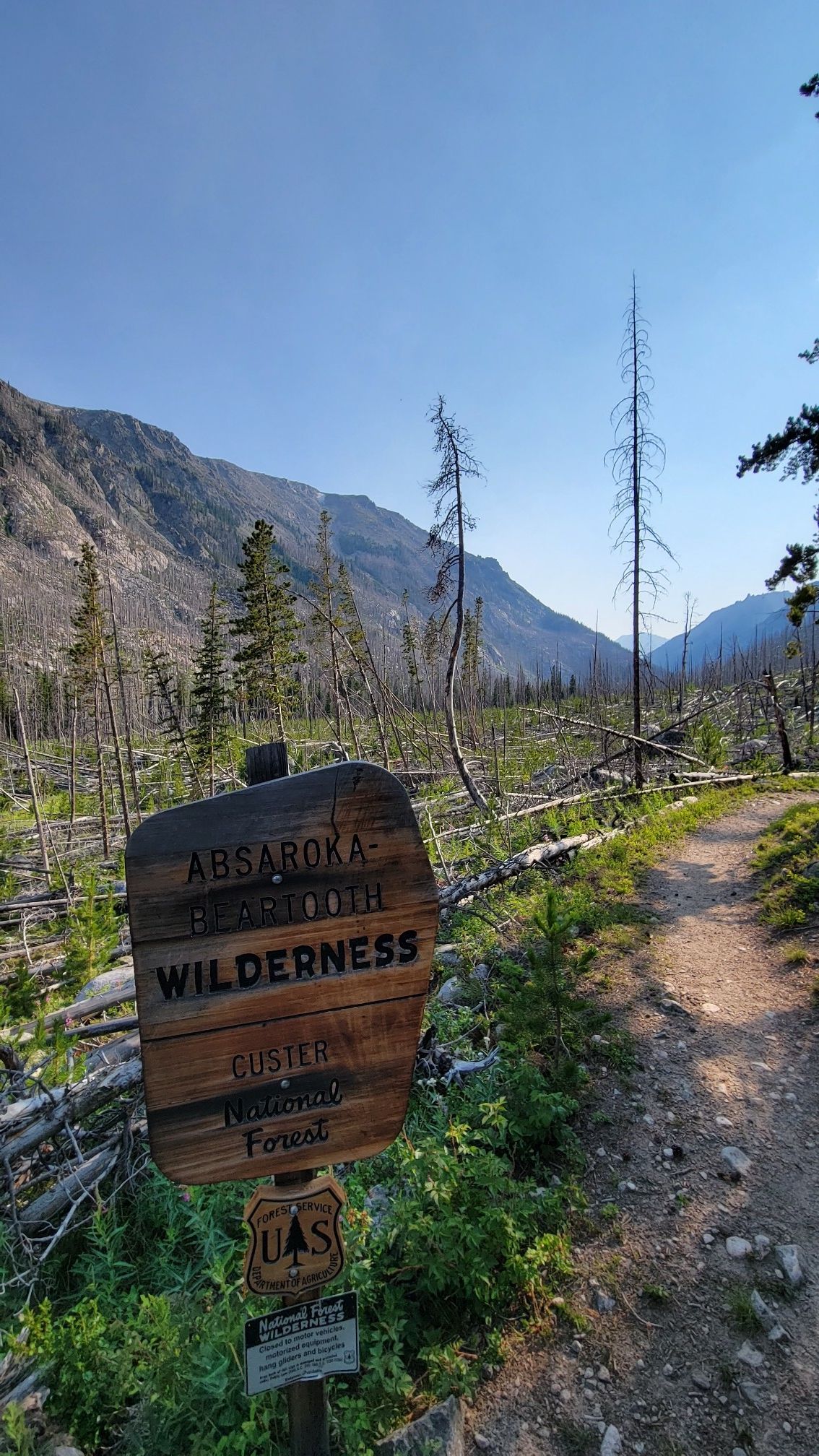 Wooden sign on a dirt path in a valley with burnt trees and mountains. - West Fork Trail #1