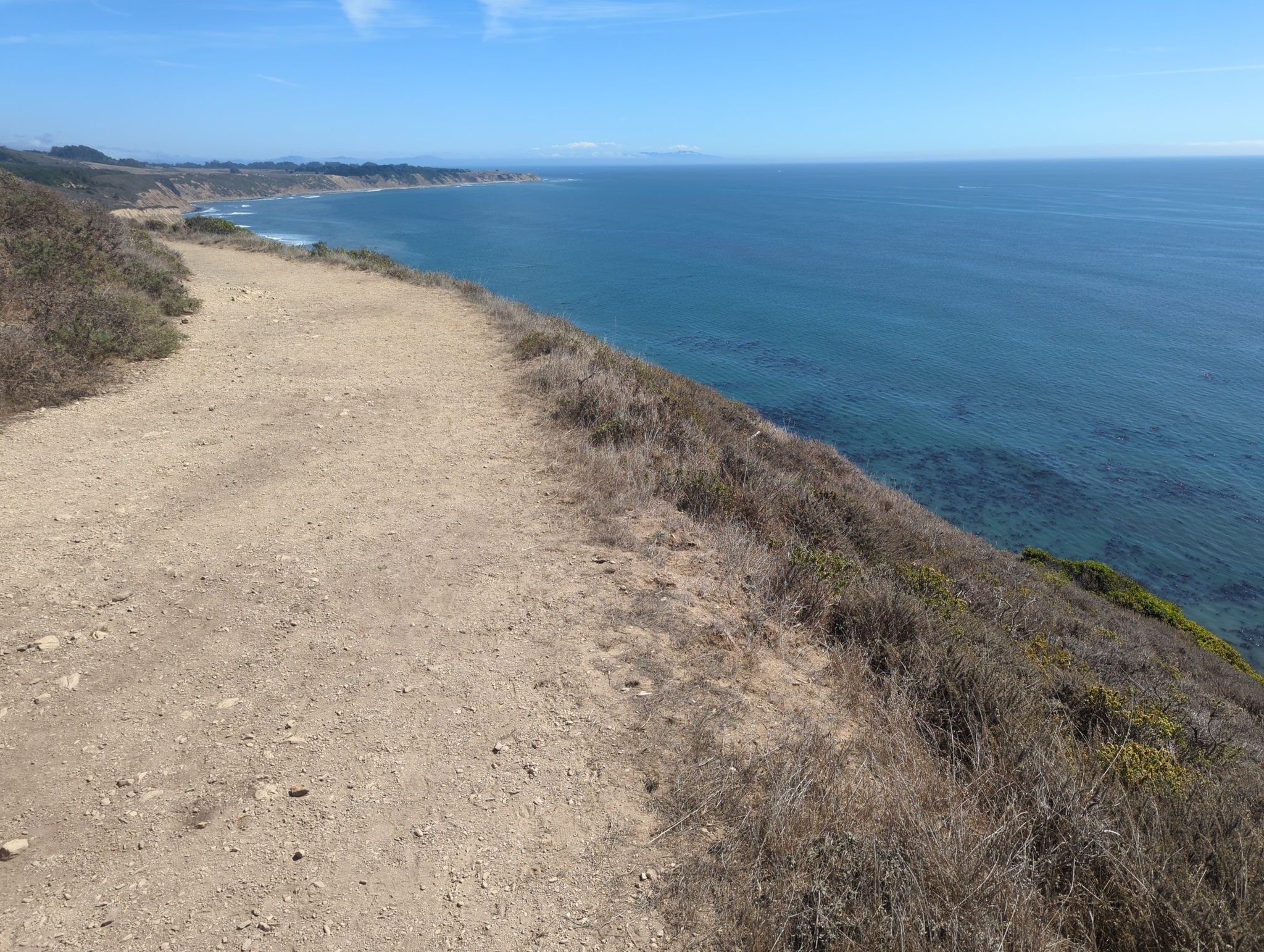 A dirt path along a cliff edge overlooking a calm blue ocean. - Coast, Lake Ranch, and Ridge Trail Loop