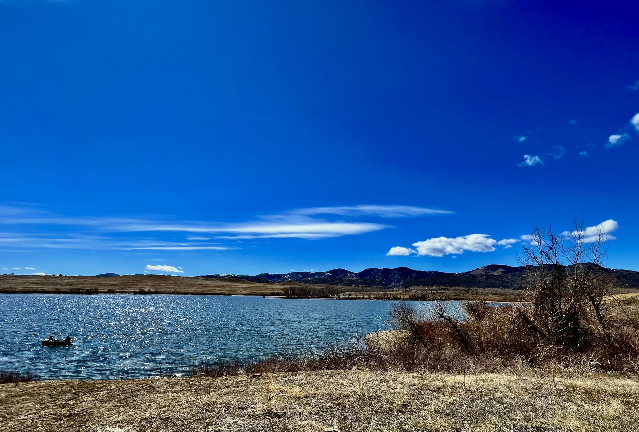 Bright lake with a small boat, dry banks, distant mountains, and blue sky. - Bear Creek Lake – Bear Creek Lake loop from Muskrat Meadows