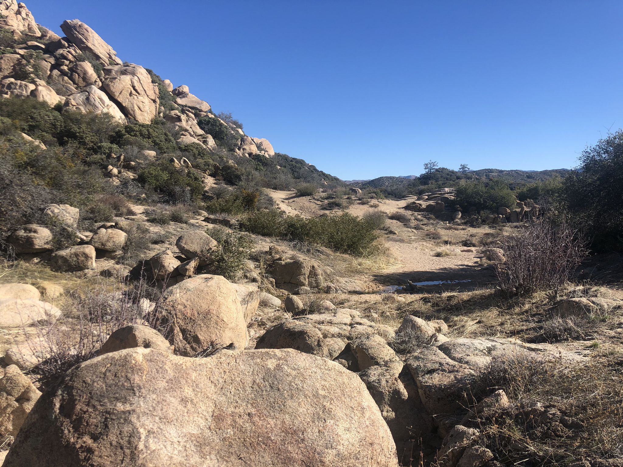 Rocky, arid landscape with a dirt path under a clear blue sky. - Arrowhead Pinnacles Trail