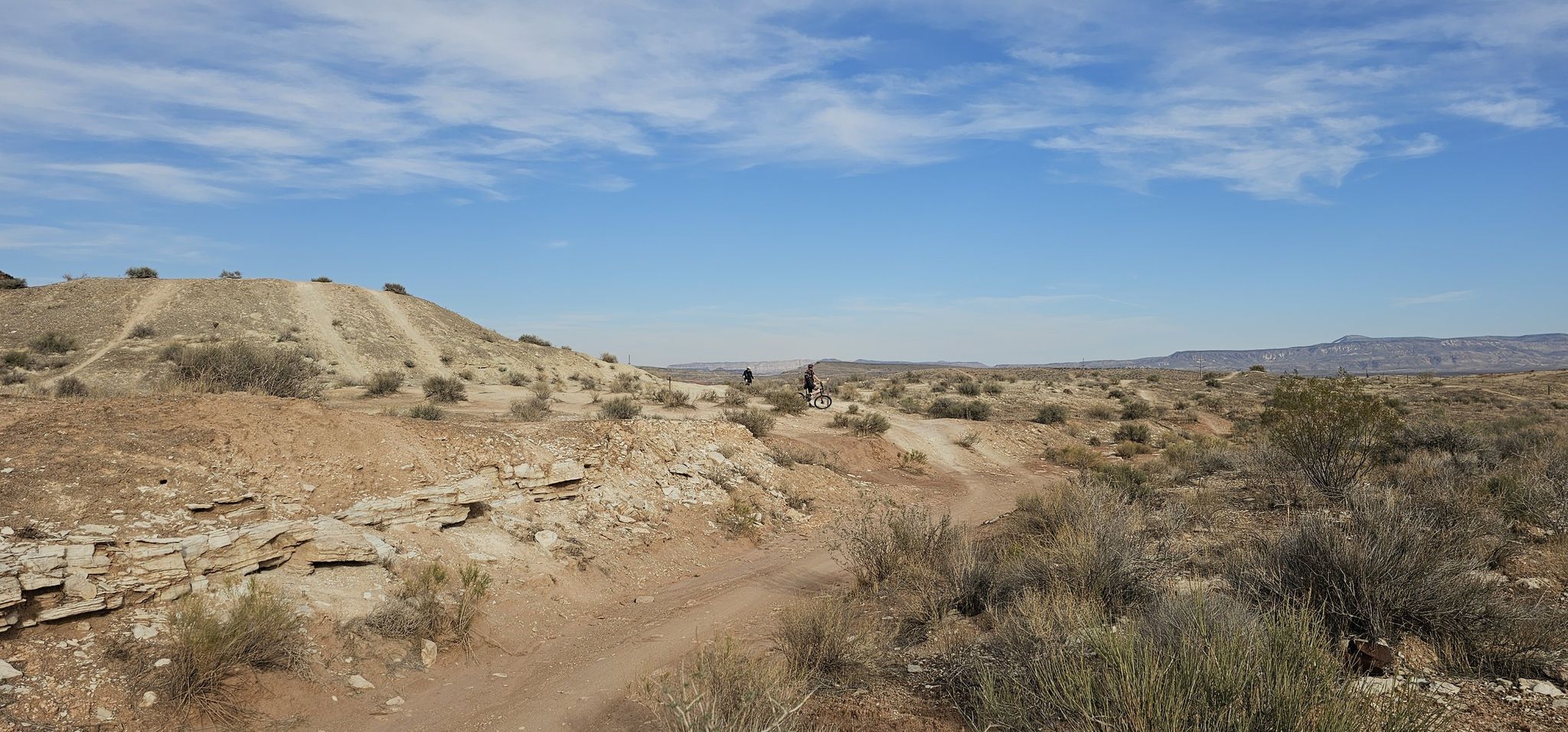 Two cyclists on a dirt trail in a vast, arid desert landscape. - Bearclaw Poppy and Snake Pit Trail