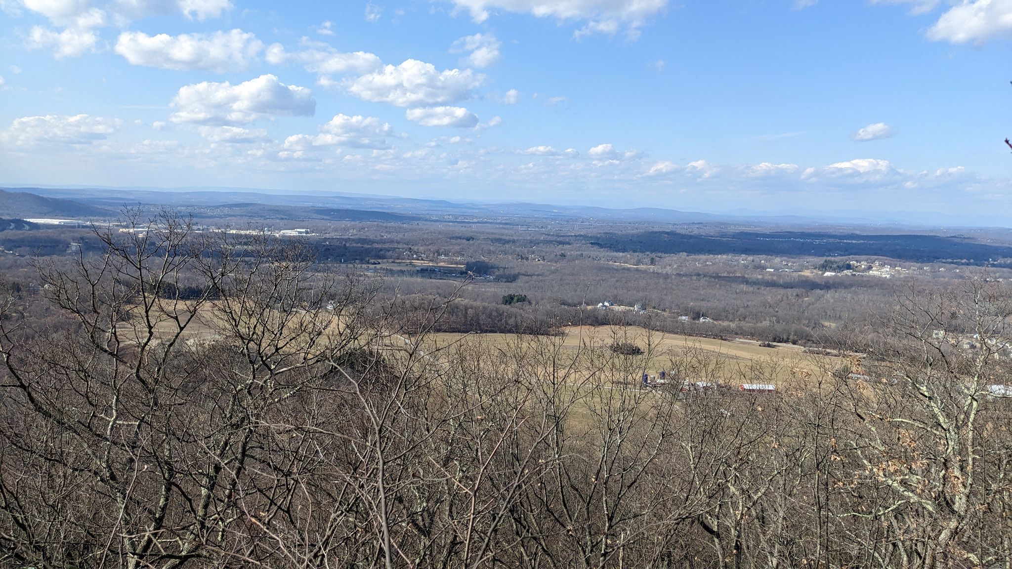Panoramic view of a valley with bare trees, fields, and distant hills under a bright sky. - Appalachian Trail: Stormville Mountain to Canopus Lake