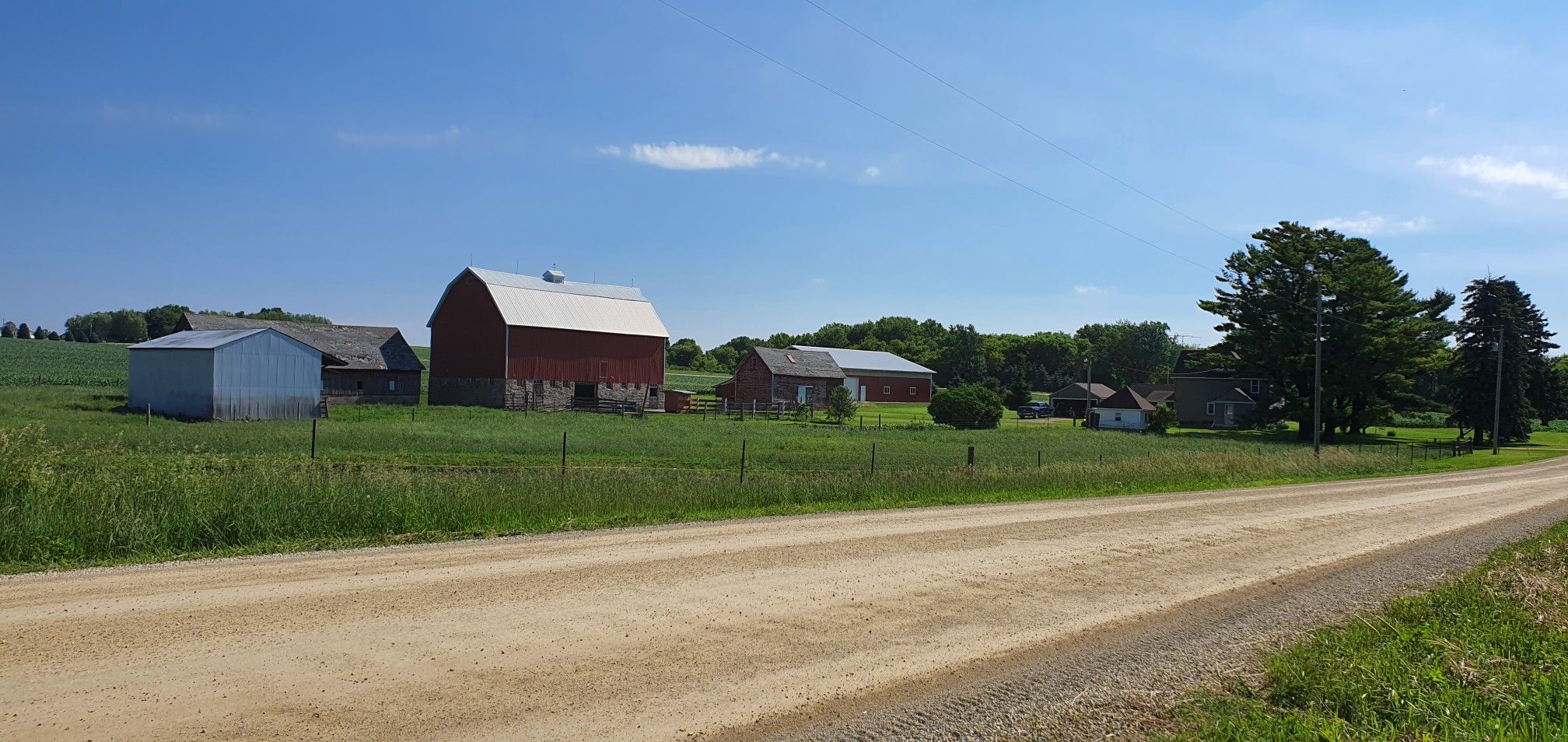 Rural landscape with farm buildings, green fields, and a dirt road. - Douglas State Trail loop from Hyvee West Circle