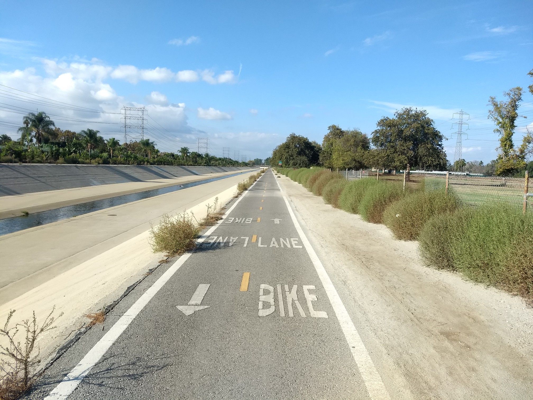 Bike lane next to a concrete channel under a partly cloudy sky. - West San Gabriel River Trail – El Dorado East Regional Park loop from Long Beach City College Liberal Arts Campus