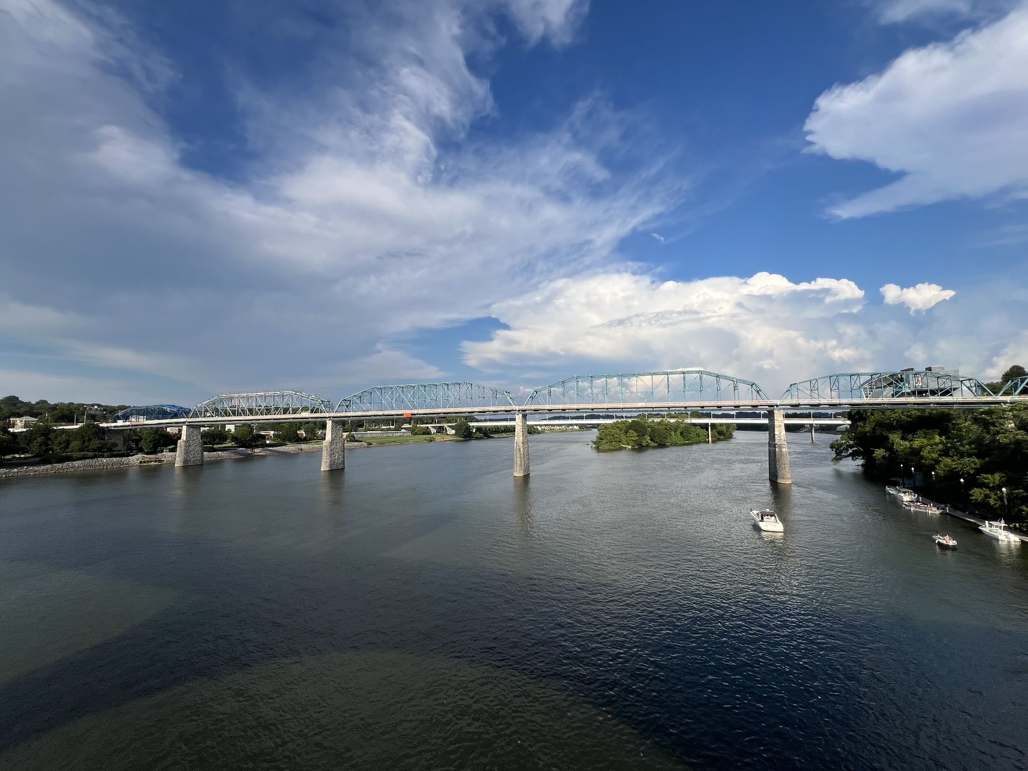 A long bridge spans a wide river under a bright, cloudy sky. - Bluff View Sculpture Garden – Hunter Museum of American Art loop from UTC McKenzie Arena