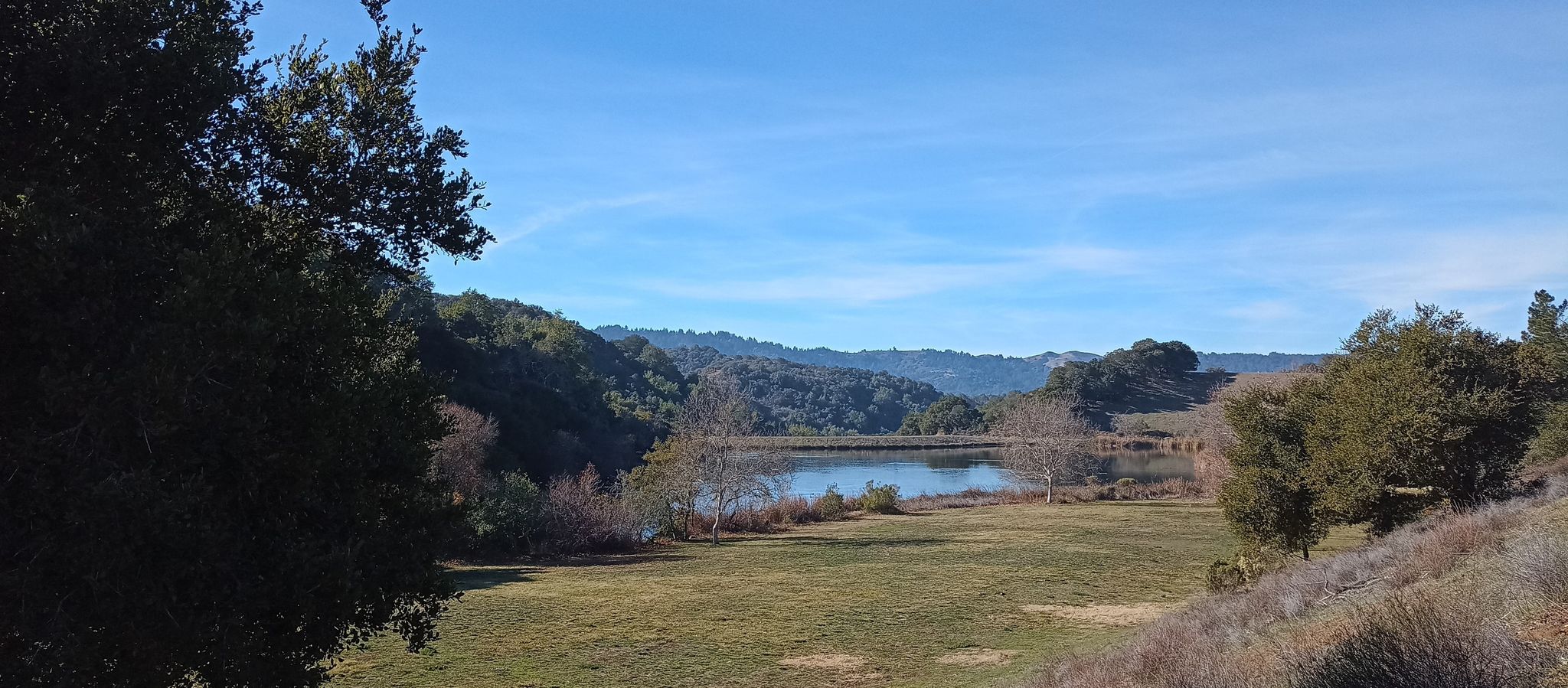 Serene lake surrounded by green fields and wooded hills under clear sky. - Boronda Lake – Lincoln Park loop from Los Altos
