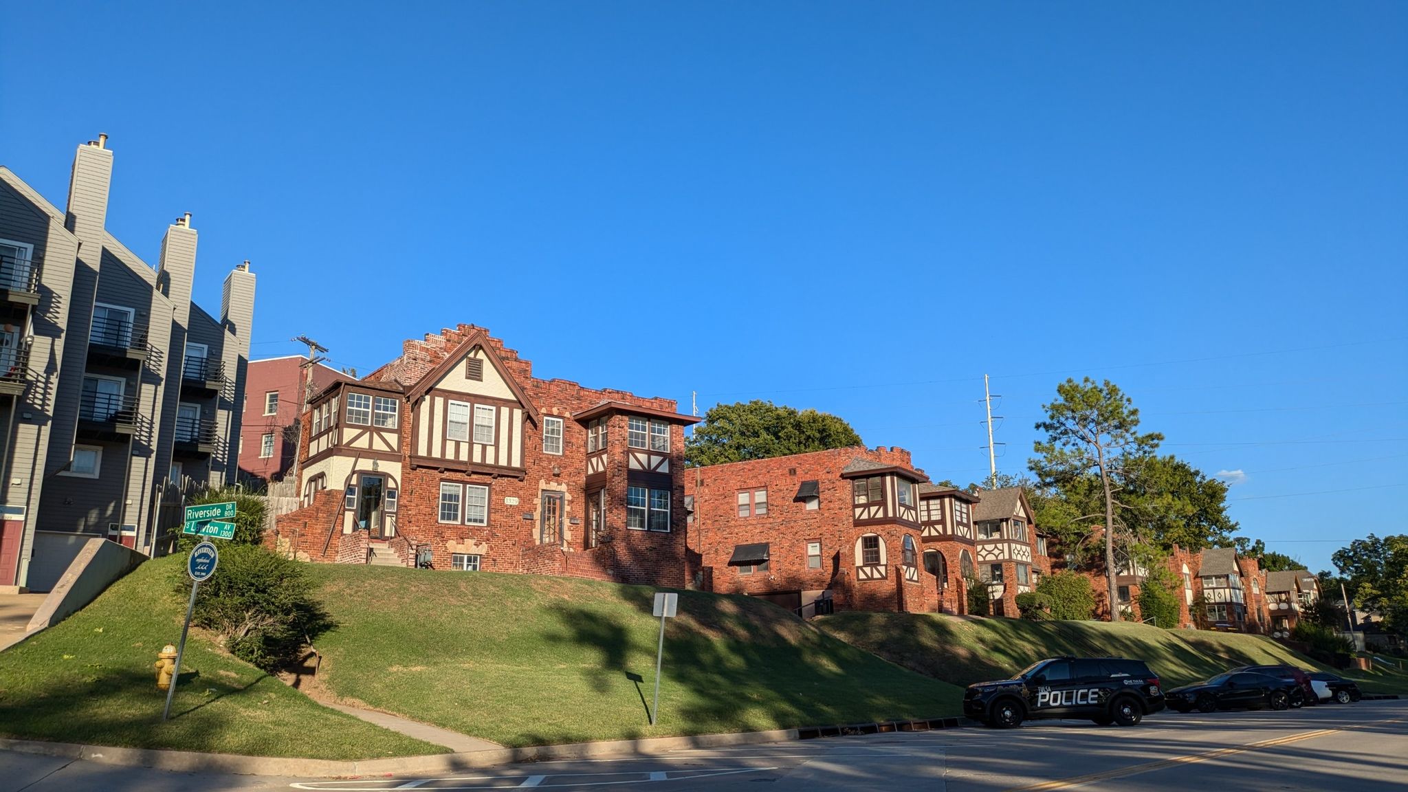 Residential street with houses on a grassy hill, police car, under clear blue sky. - Tuckabache and River Parks East Bank Trail Loop