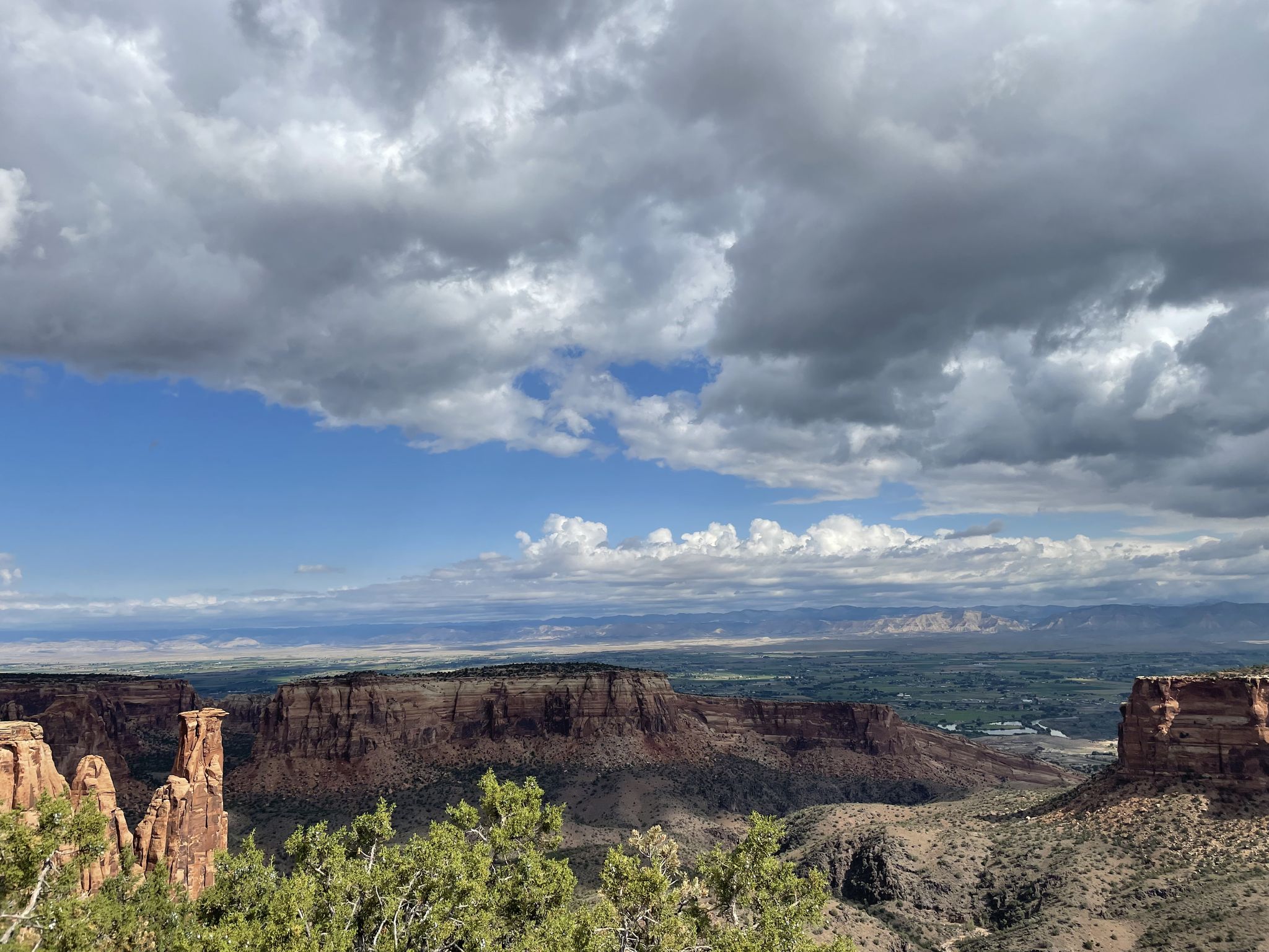 Canyon landscape with rock formations and green valley under a dramatic cloudy sky. - Redlands loop