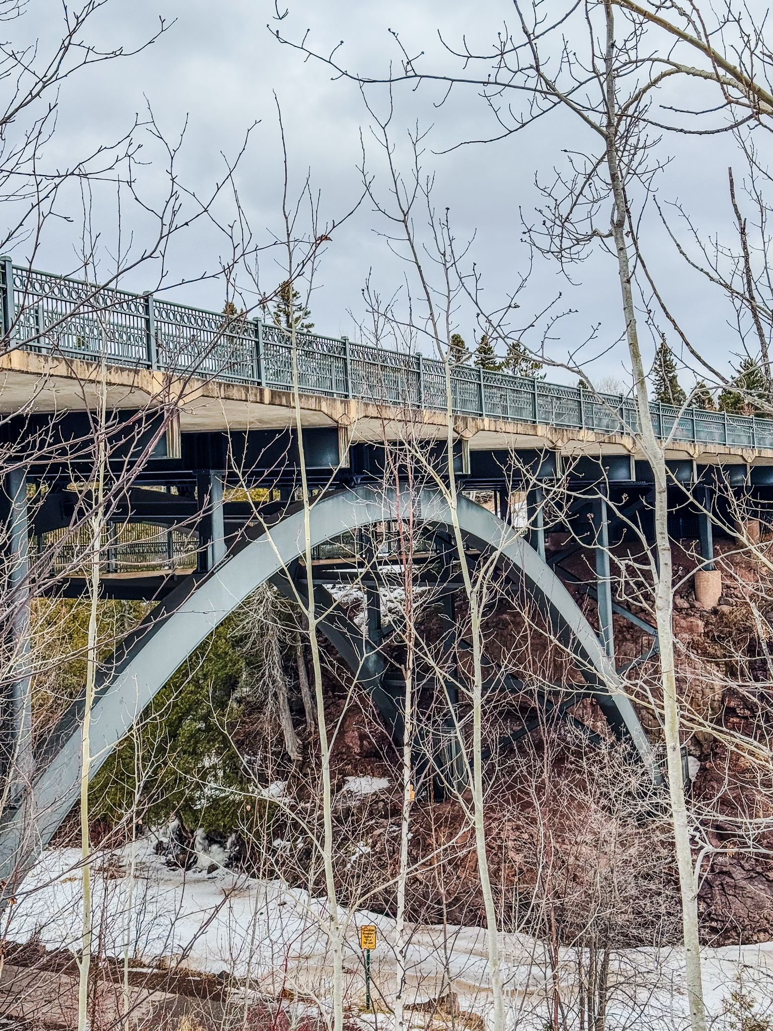 Large arched bridge spans over a snowy landscape with bare trees in winter. - Fifth Falls – Upper Falls loop from Gooseberry Falls State Park