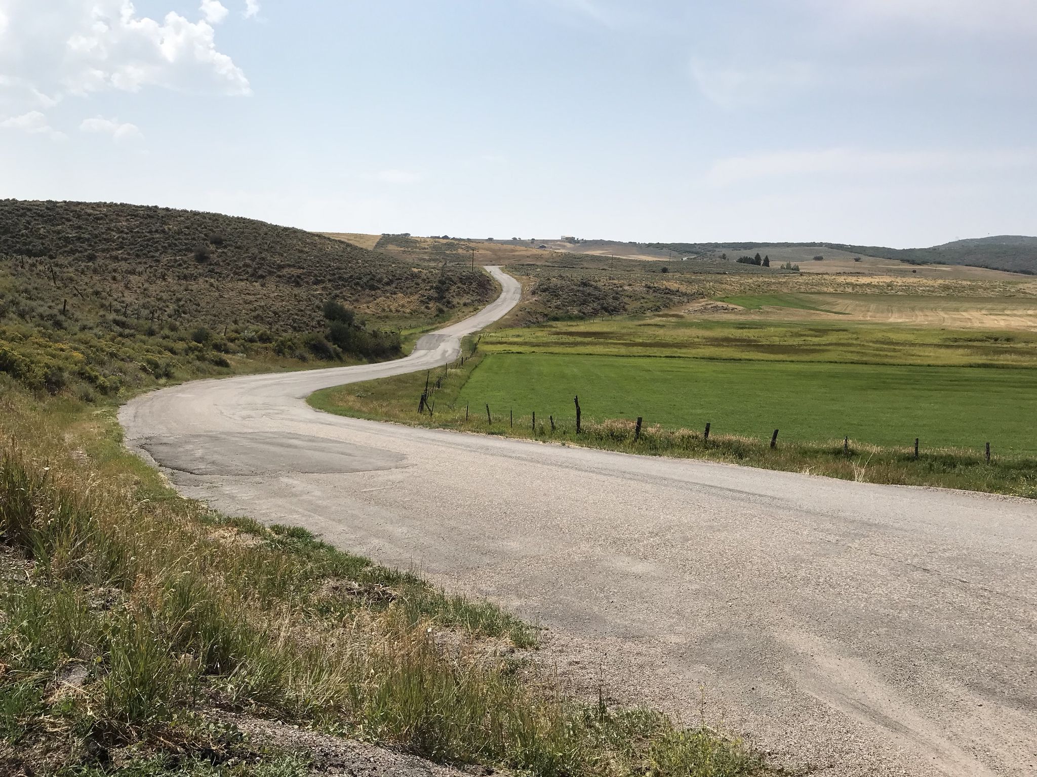 A winding paved road through green and brown rolling hills under a bright sky. - Old Coulter and Missouri Heights Schoolhouse loop from Carbondale