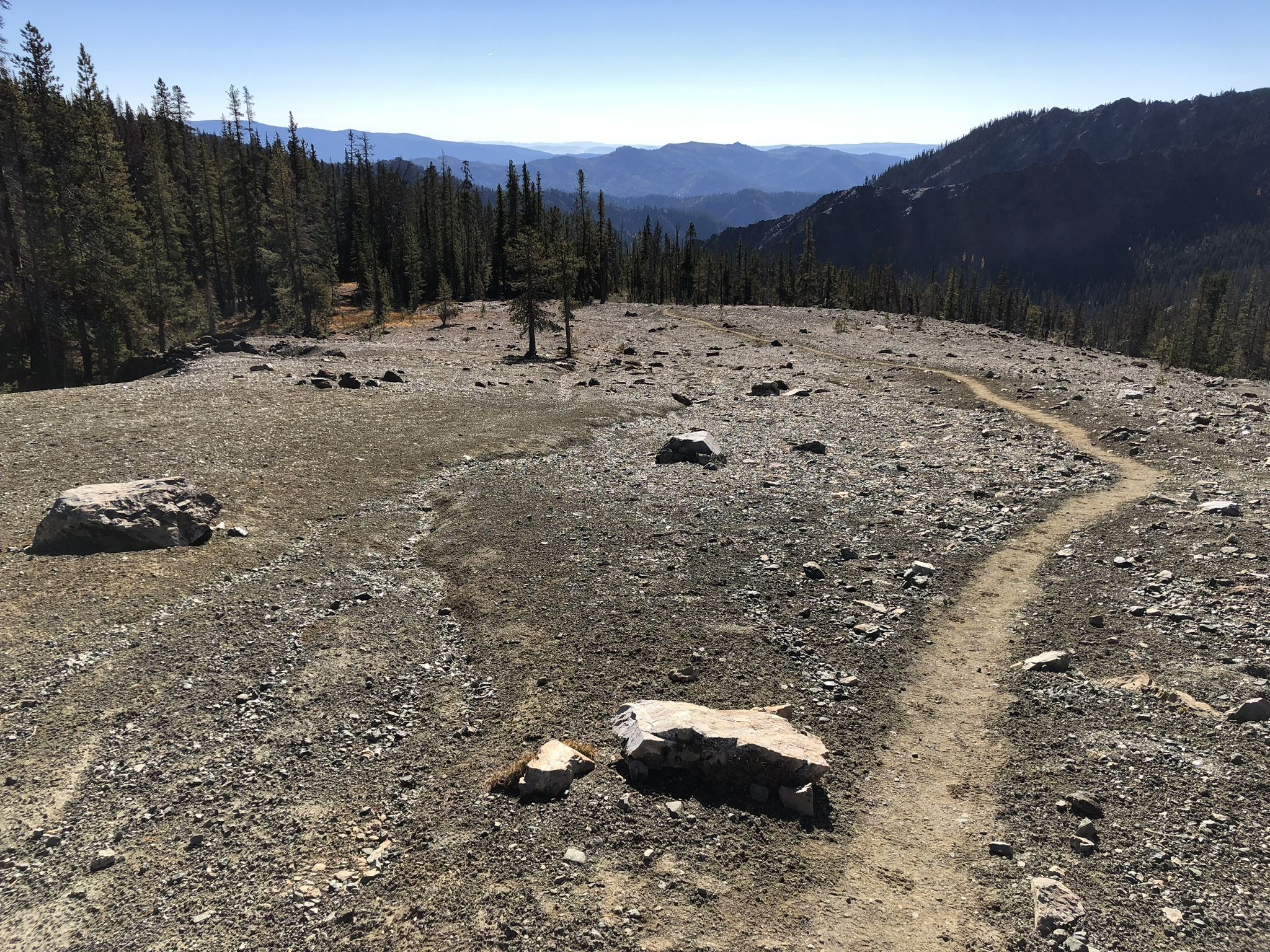A dirt path winds through a rocky, open mountain landscape under clear skies. - Navaho Peak via Stafford Creek Trail