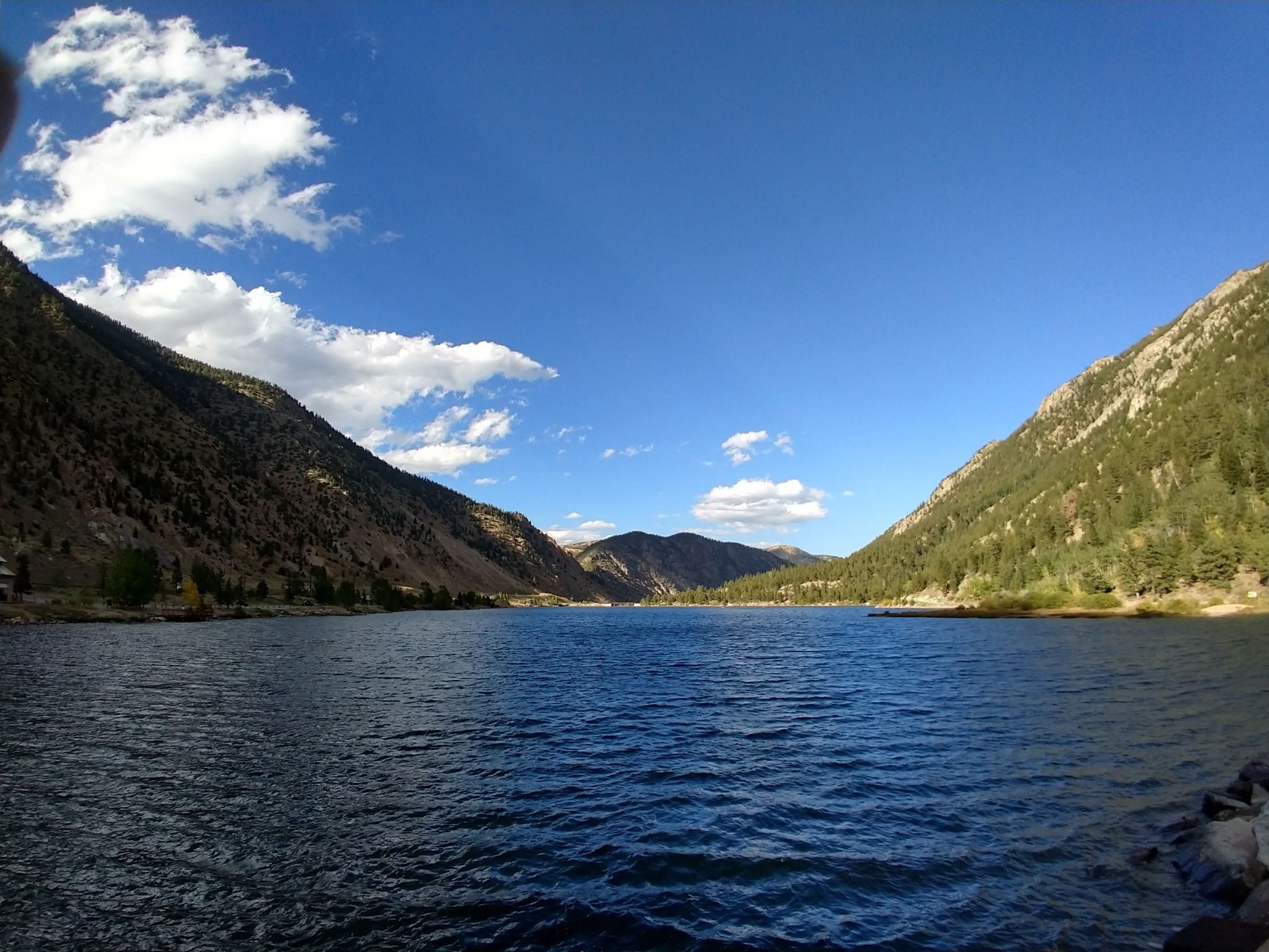Deep blue lake surrounded by steep, forested mountains under a bright sky. - Tom Bennhoff Lake Trail loop