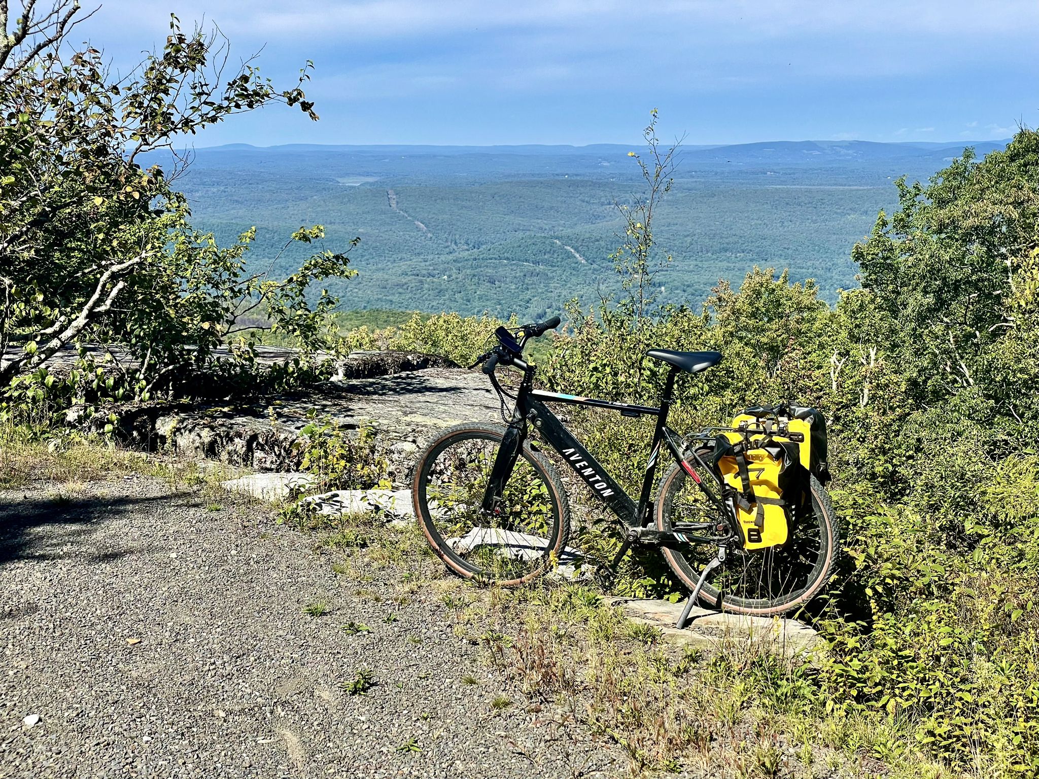 A black bicycle with yellow bags parked on a gravel path overlooking a valley. - Long Path and Mine Hole Trail
